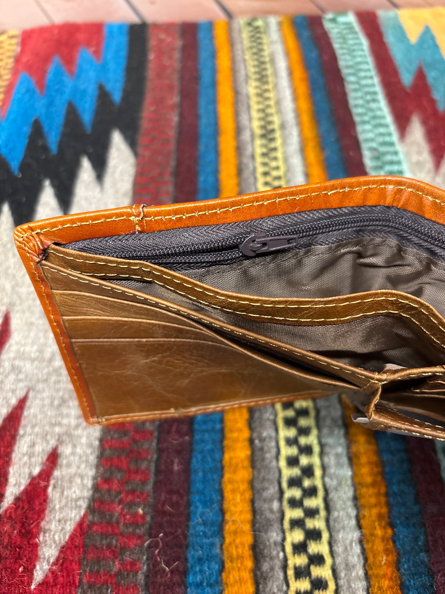 Brown leather wallet open against a view of the inside zipper pocket with fabric background.