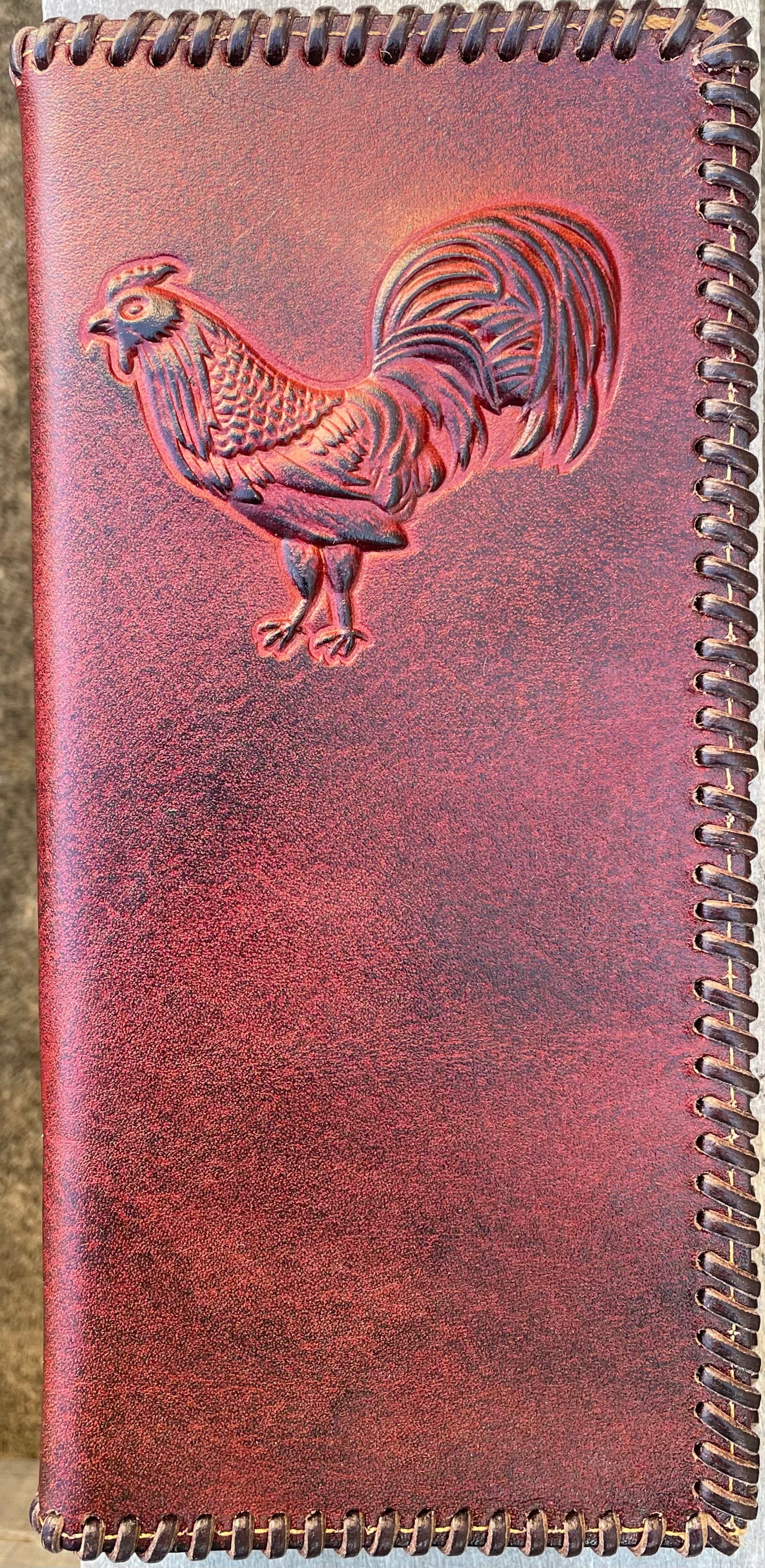 Antique Brown leather wallet with embossed rooster design on a wooden surface