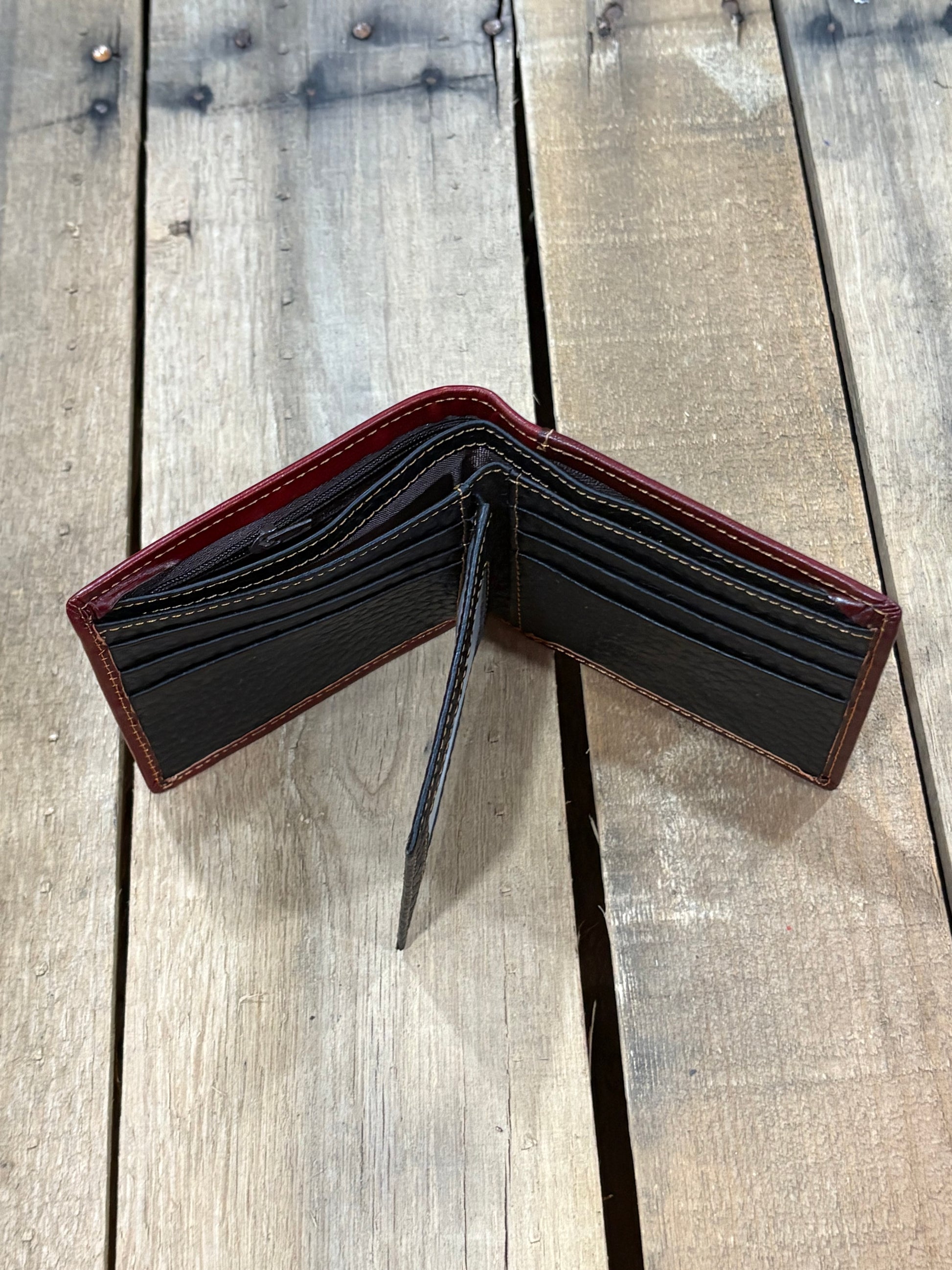 Black leather inside wallet with card slots, 2 cash compartments, and back zipper on a wooden surface