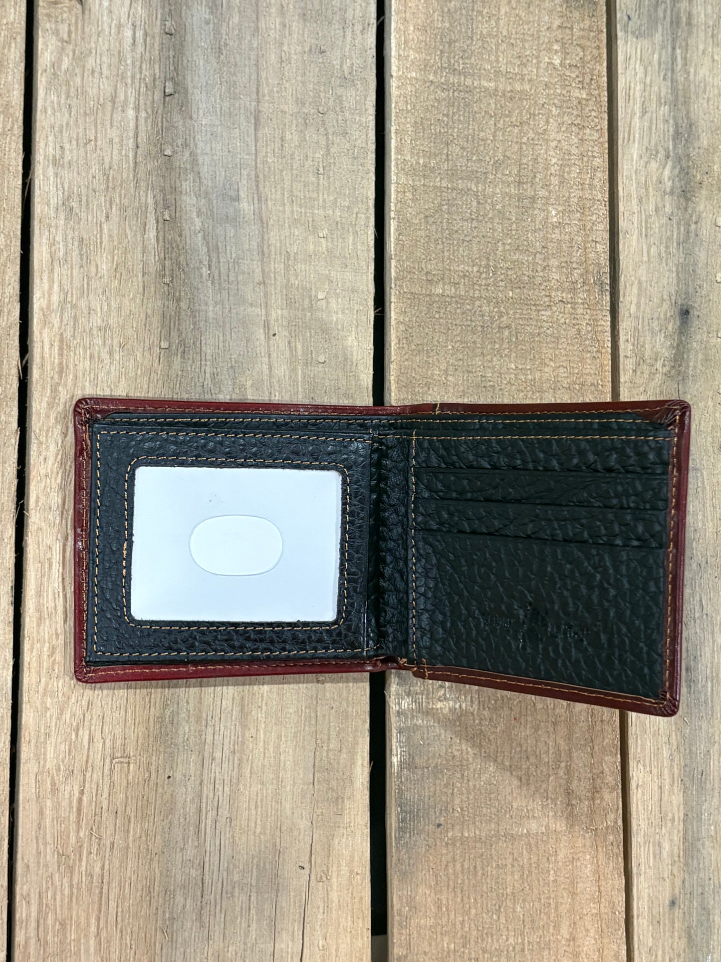 Black pebbled leather inside wallet with three card slots and one ID window slot on a wooden surface