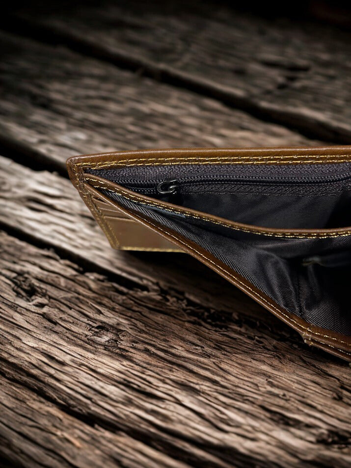 Inside view of the Zipper pocket in a Brown leather wallet open on a wooden surface