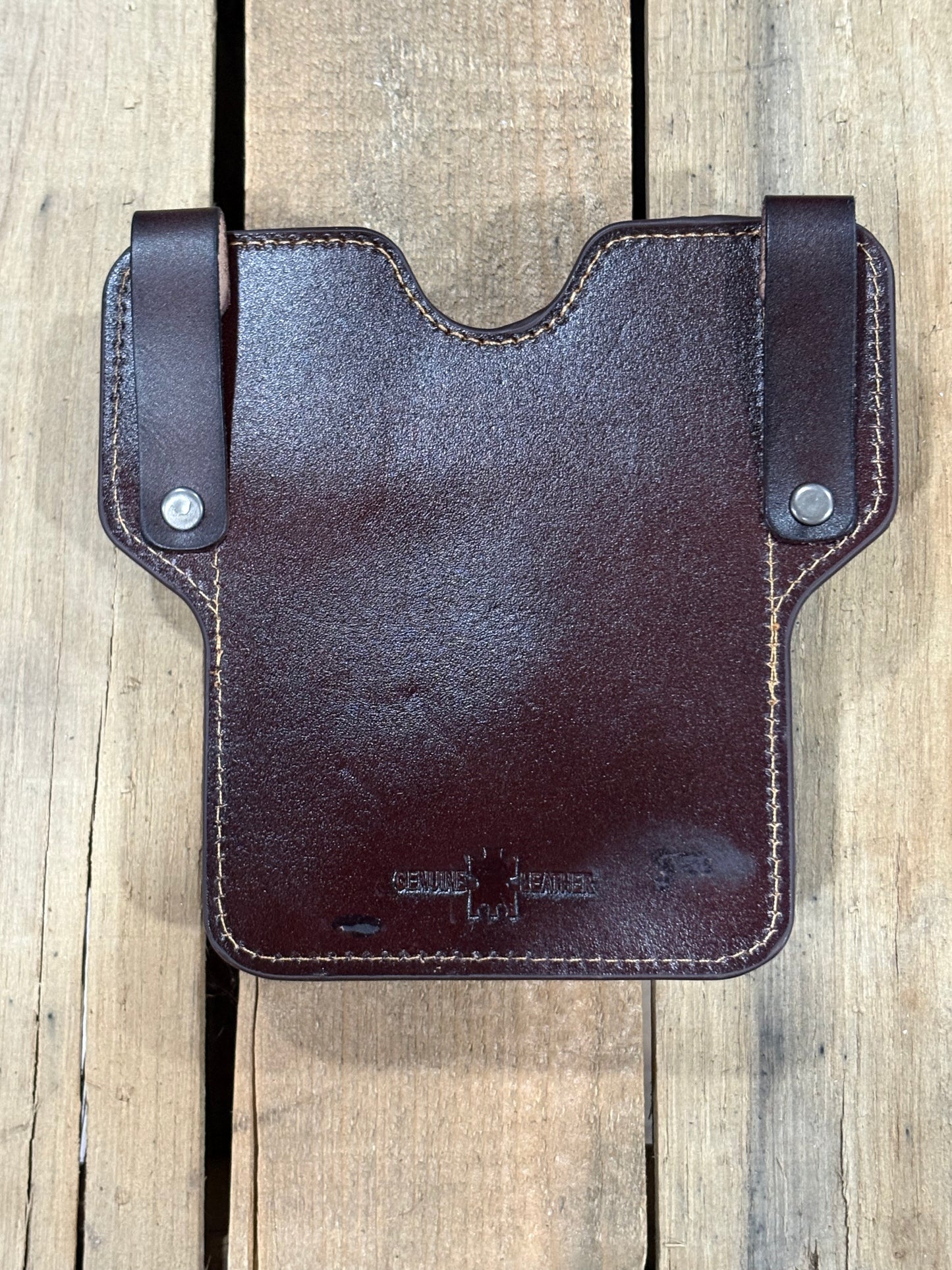Back view of a coffee brown leather phonecase on a wooden surface