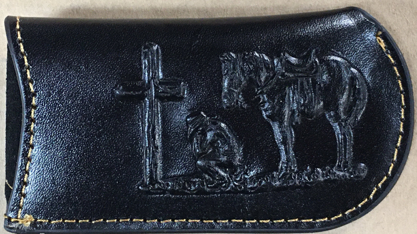 Black leather case with embossed design of a cross, horse, and person on a beige background