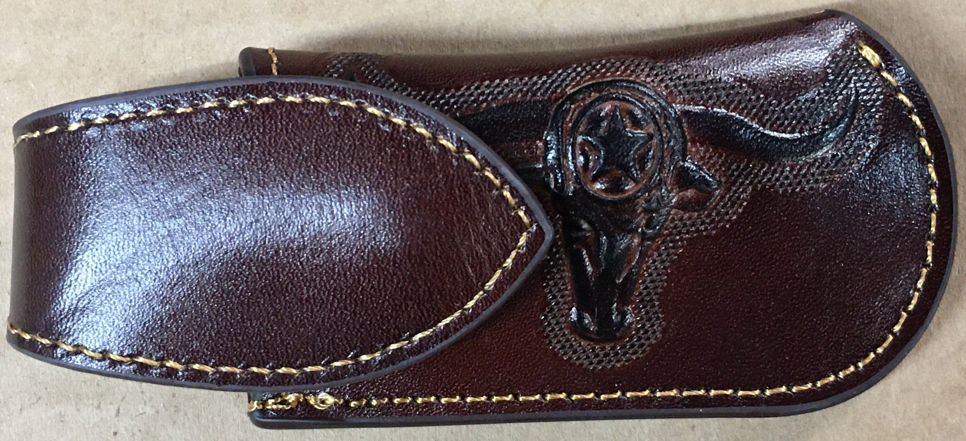 Coffee Brown leather sheath with a bull head emblem on a beige background