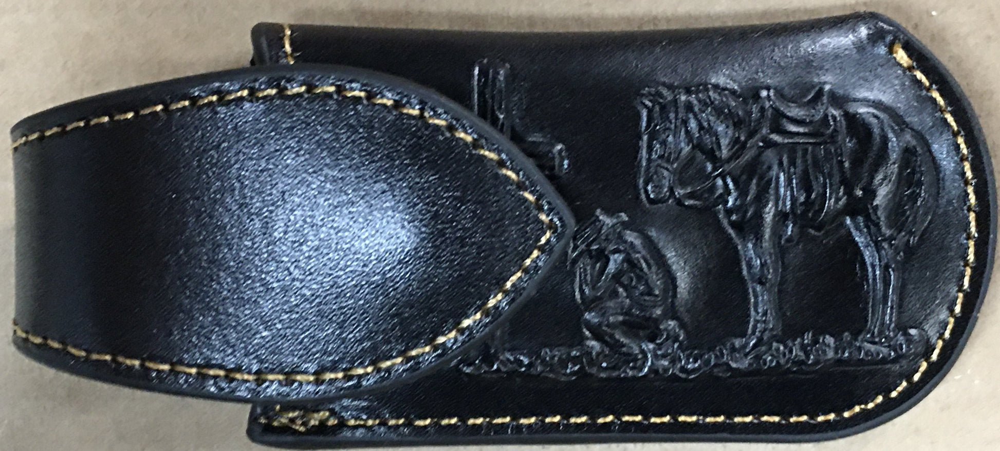 Black leather belt with embossed design on a beige background