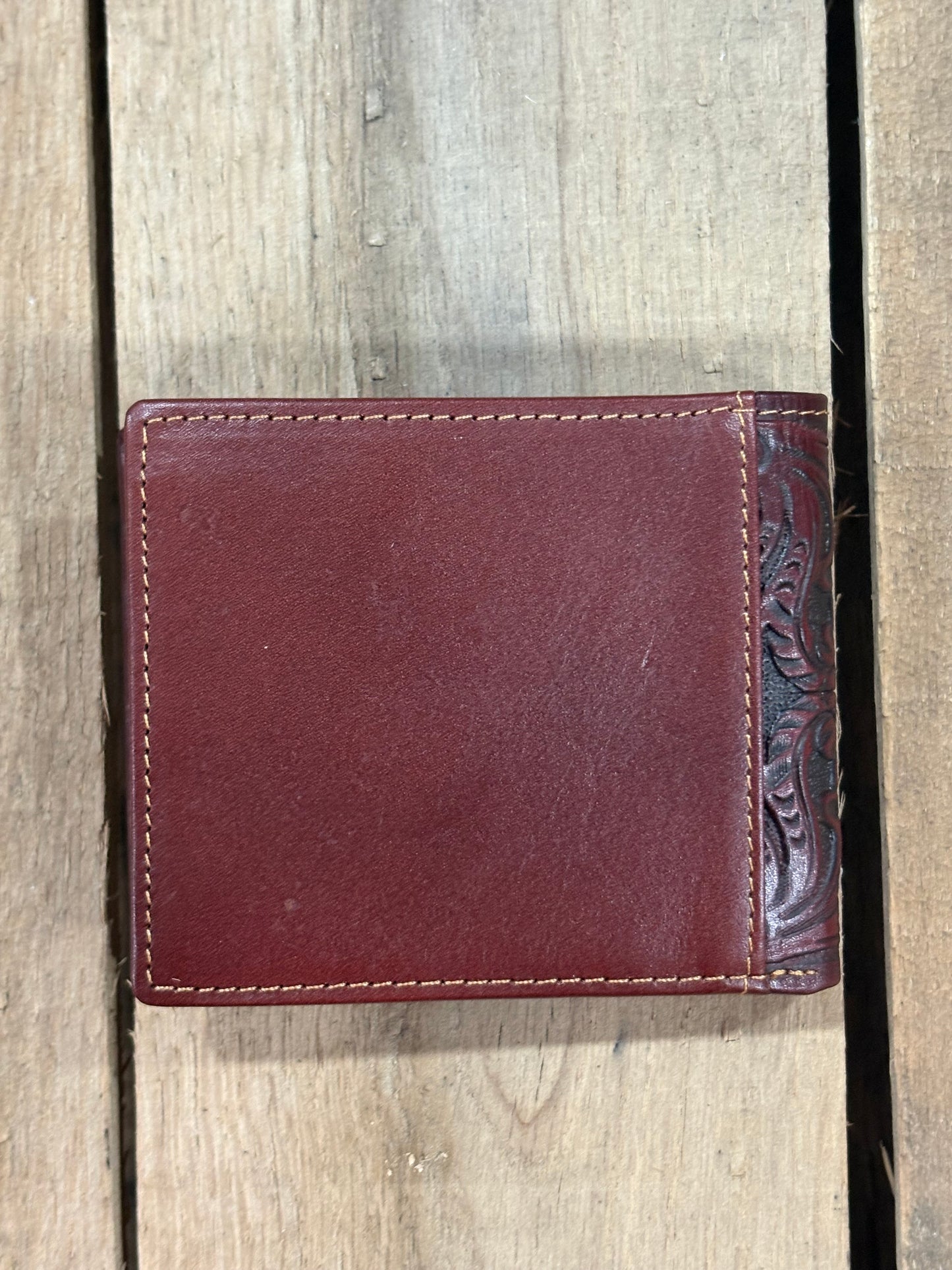 Brown smooth leather wallet with intricate stitching on a wooden surface