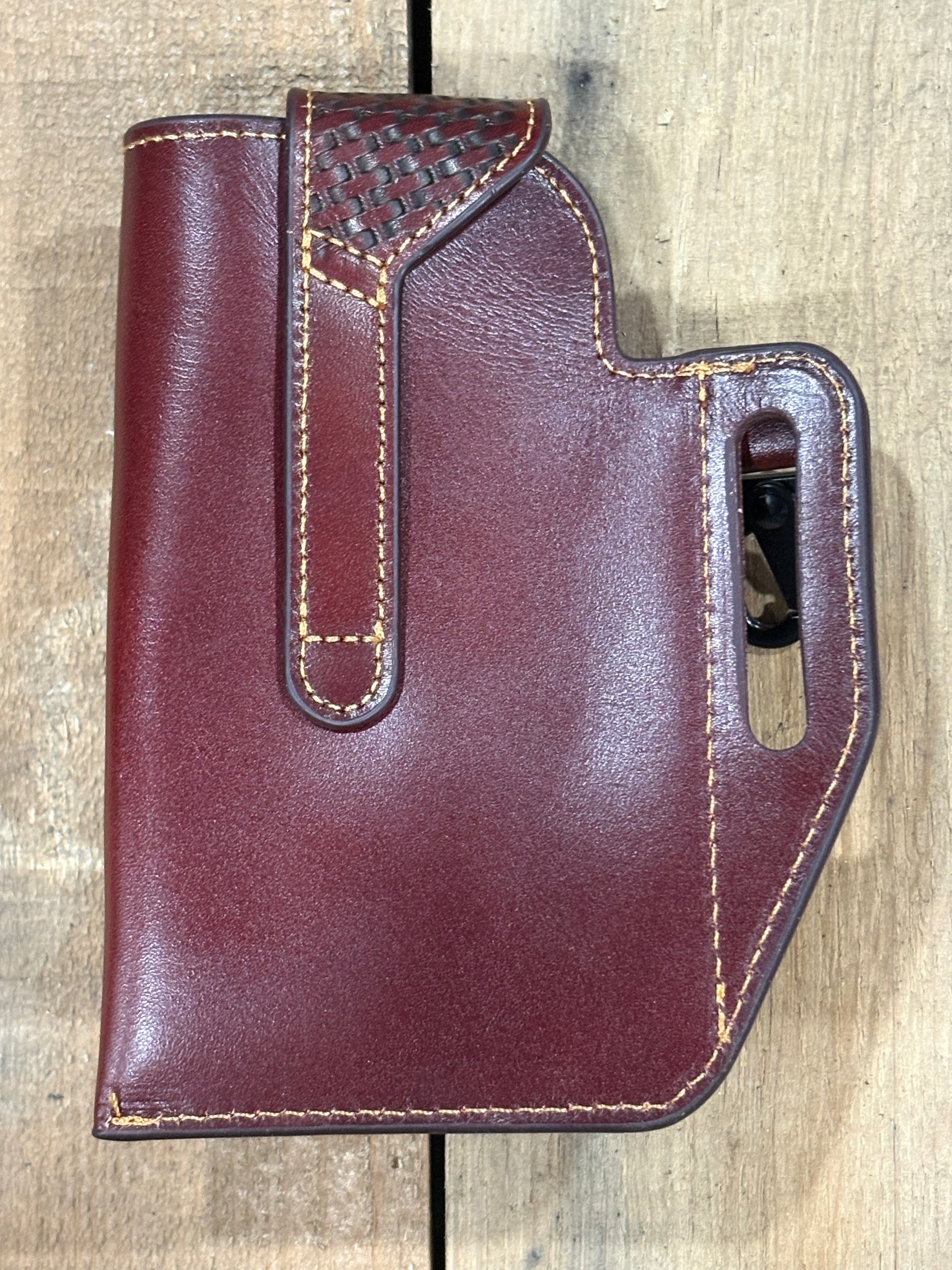 Back view of a brown leather holster on a wooden surface