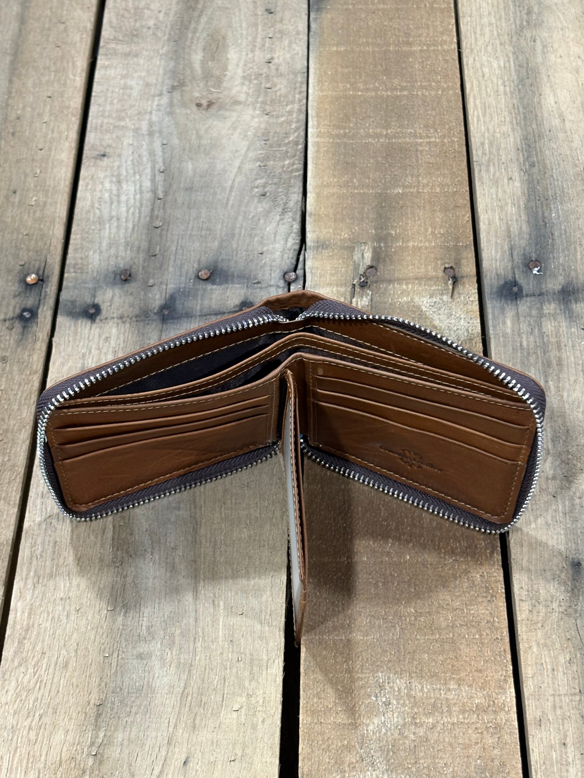 Brown leather wallet showing two currency compartments and all the card slots on a wooden surface