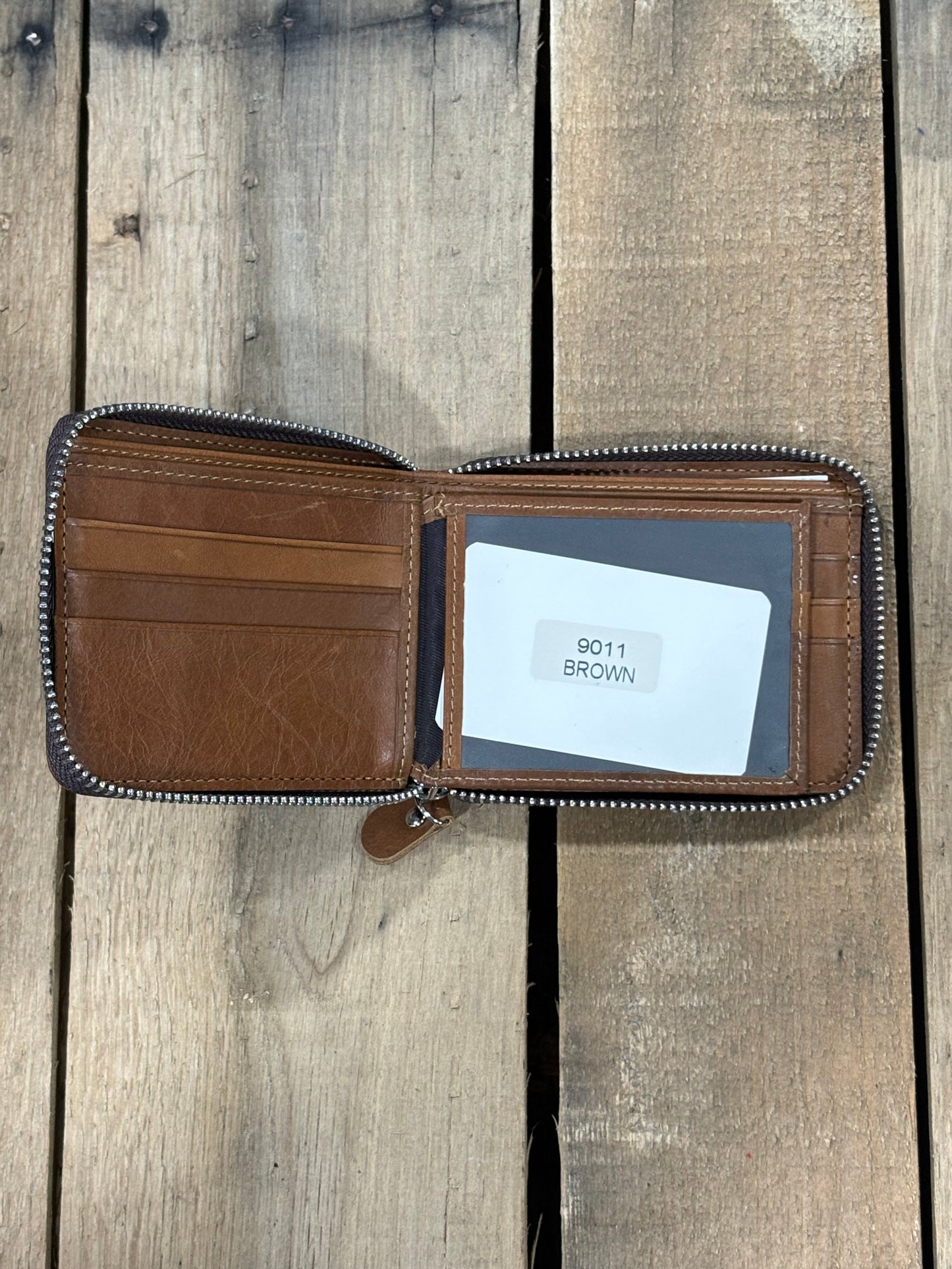 Brown leather wallet with a card inside the ID window slot and three card slots on a wooden surface