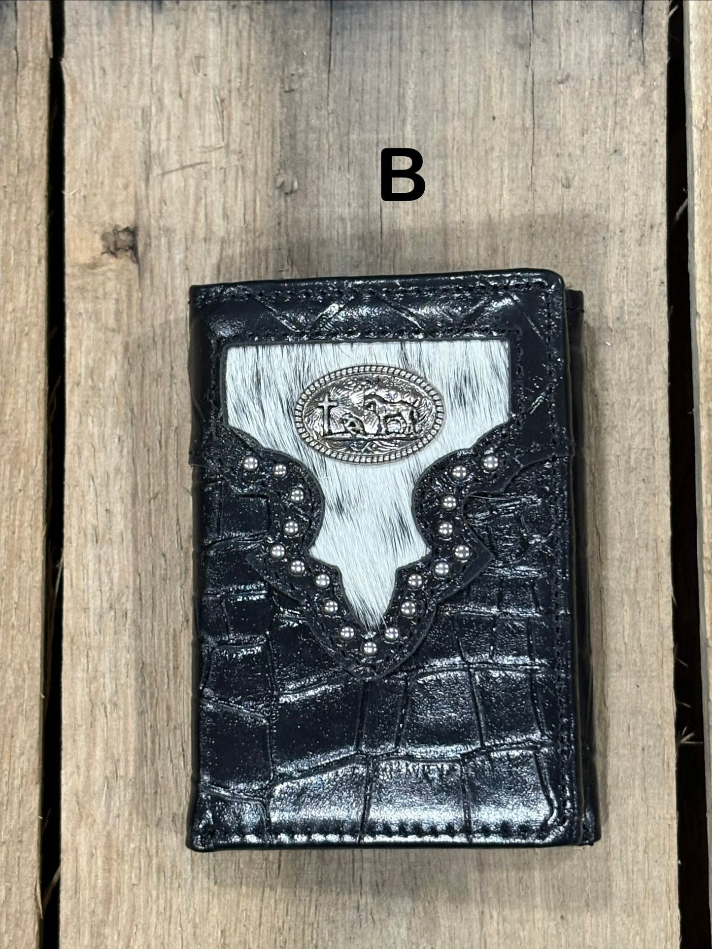 Black leather alligator print wallet with black and white hairon cowhide, praying cowboy concho on a wooden surface