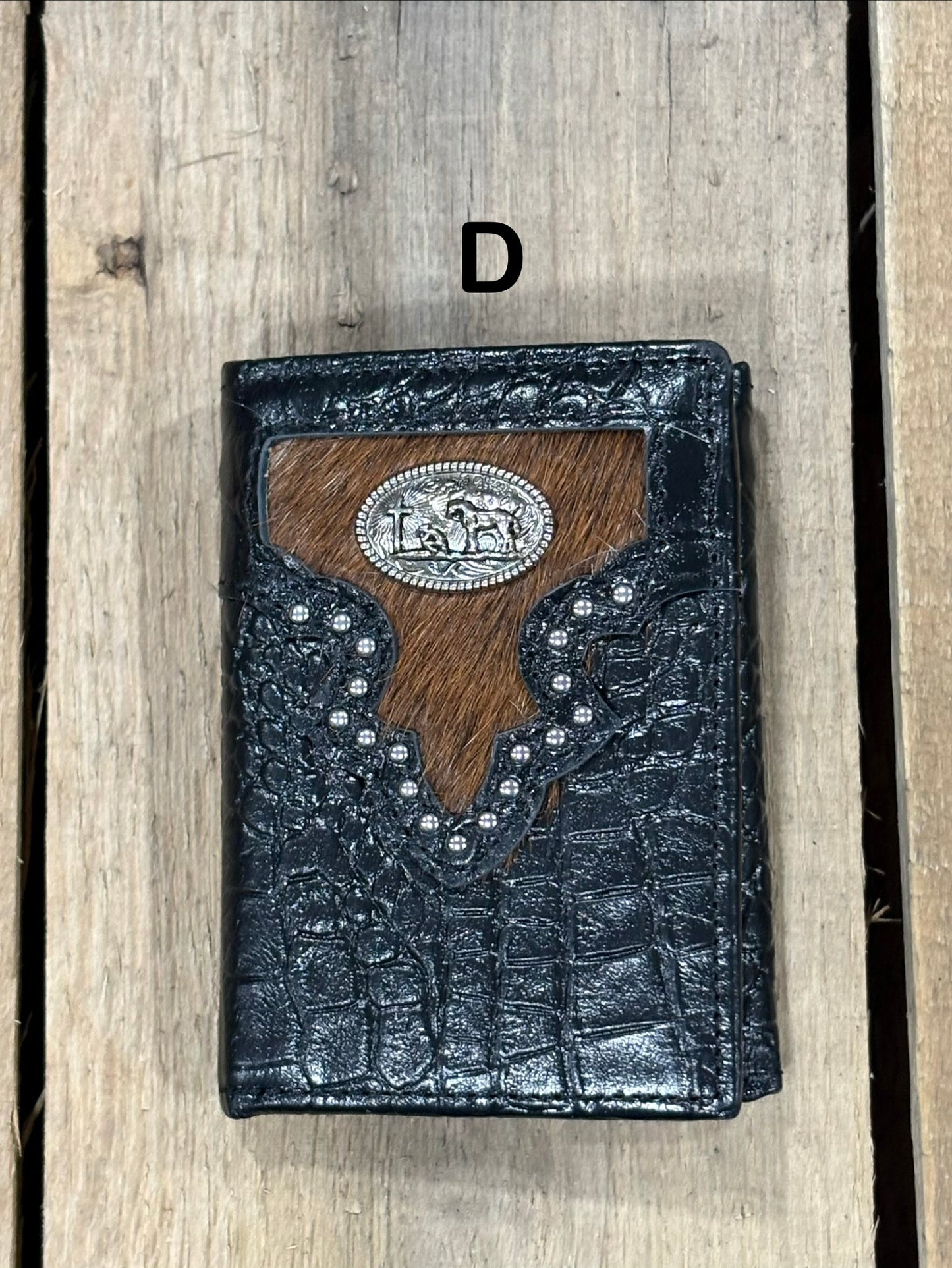 Black leather alligator print wallet with brown hairon cowhide, praying cowboy concho on a wooden surface