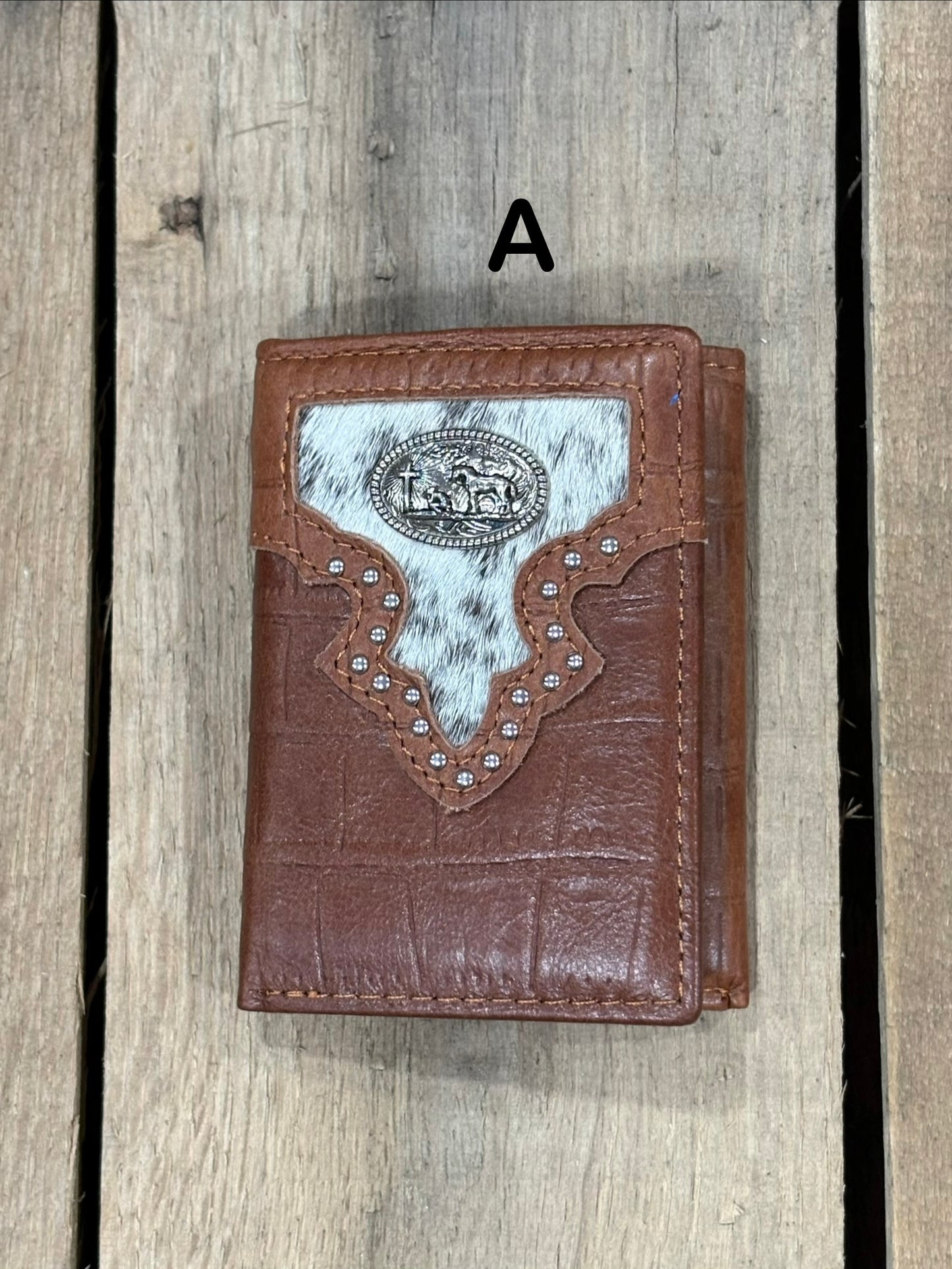 Brown leather alligator print wallet with black and white hairon cowhide, praying cowboy concho on a wooden surface