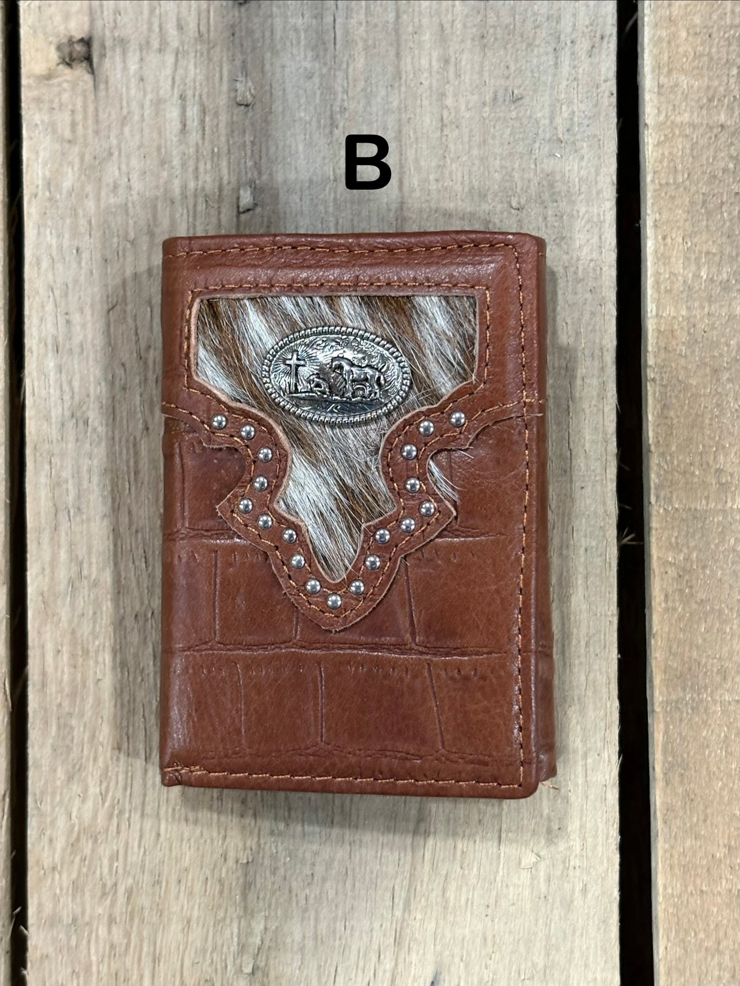 Brown leather alligator print wallet with black and white hairon cowhide, praying cowboy concho on a wooden surface