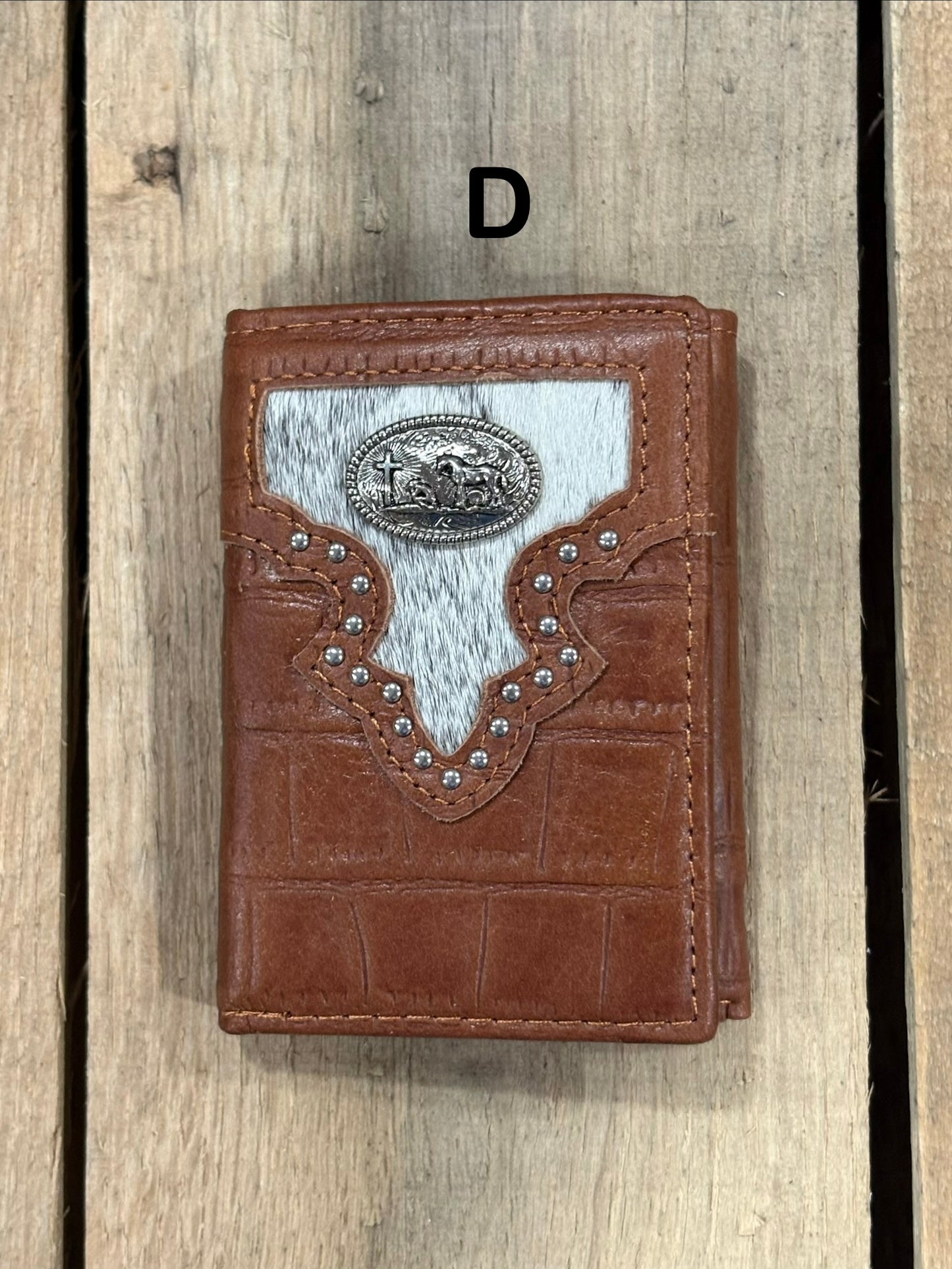 Brown leather alligator print wallet with black and white hairon cowhide, praying cowboy concho on a wooden surface