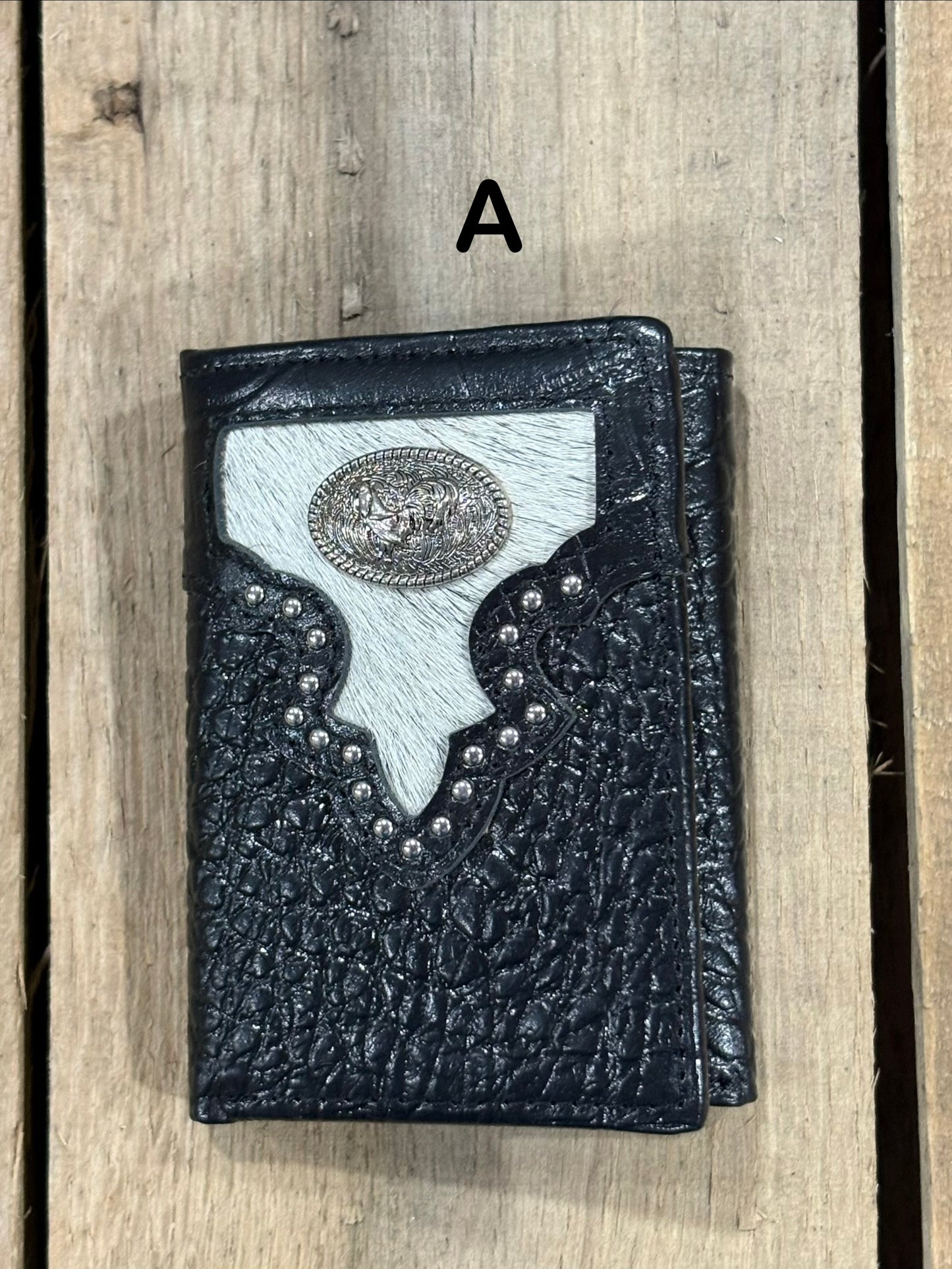 Black leather alligator print wallet with hairon cowhide and silver rooster concho on a wooden surface