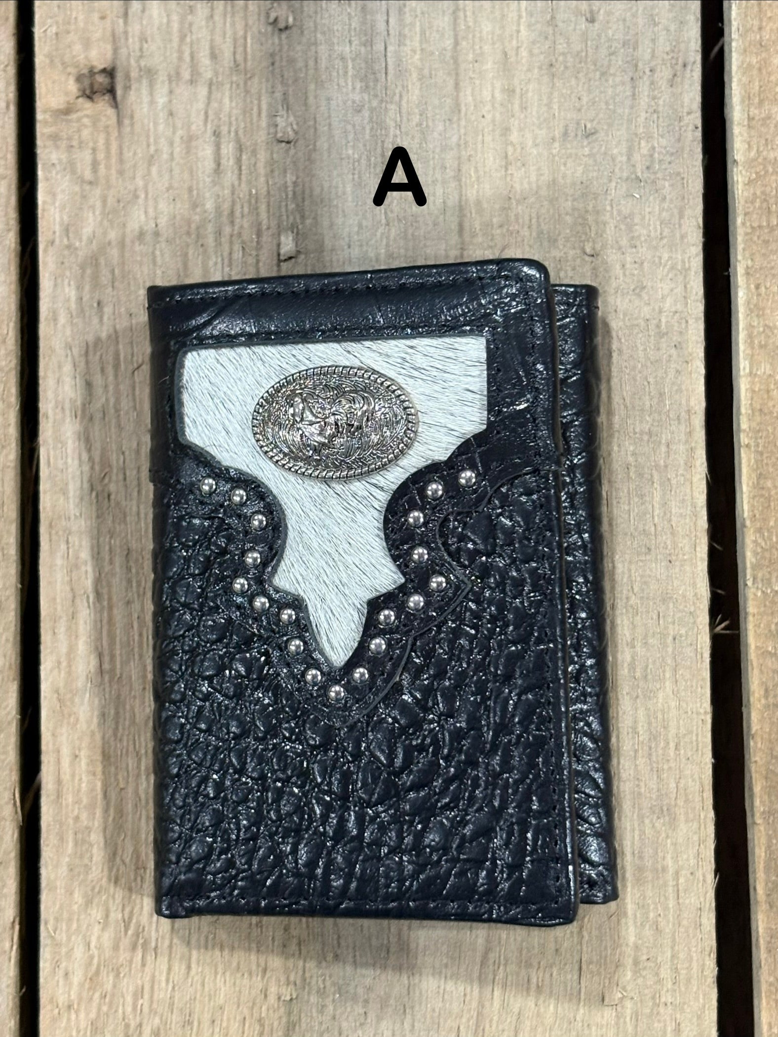 Black leather alligator print wallet with hairon cowhide and silver rooster concho on a wooden surface