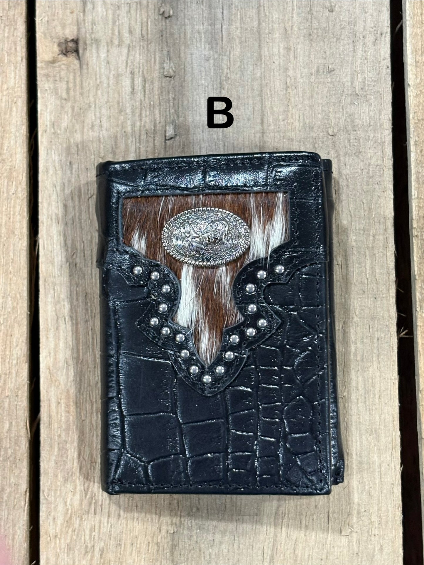 Black leather alligator print wallet with hairon cowhide and silver rooster concho on a wooden surface