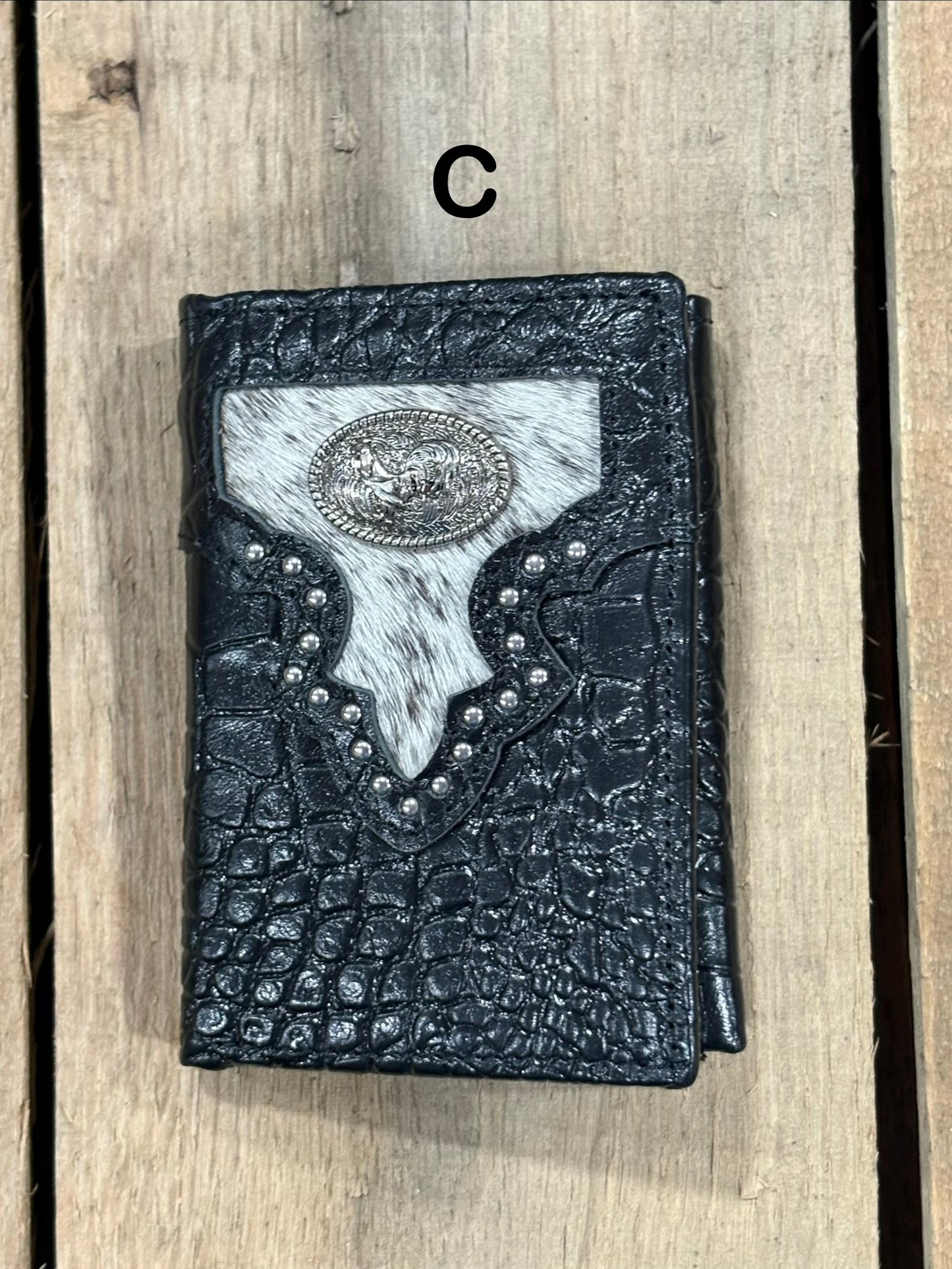 Black leather alligator print wallet with hairon cowhide and silver rooster concho on a wooden surface