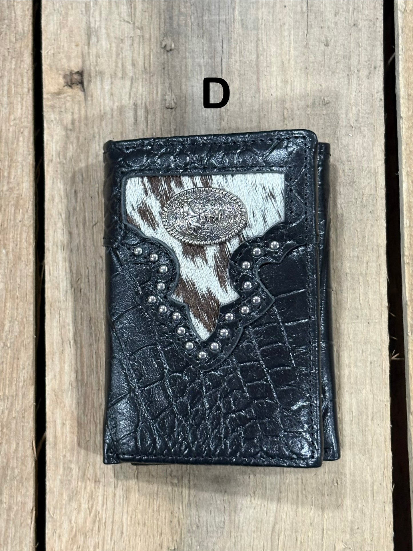 Black leather alligator print wallet with hairon cowhide and silver rooster concho on a wooden surface