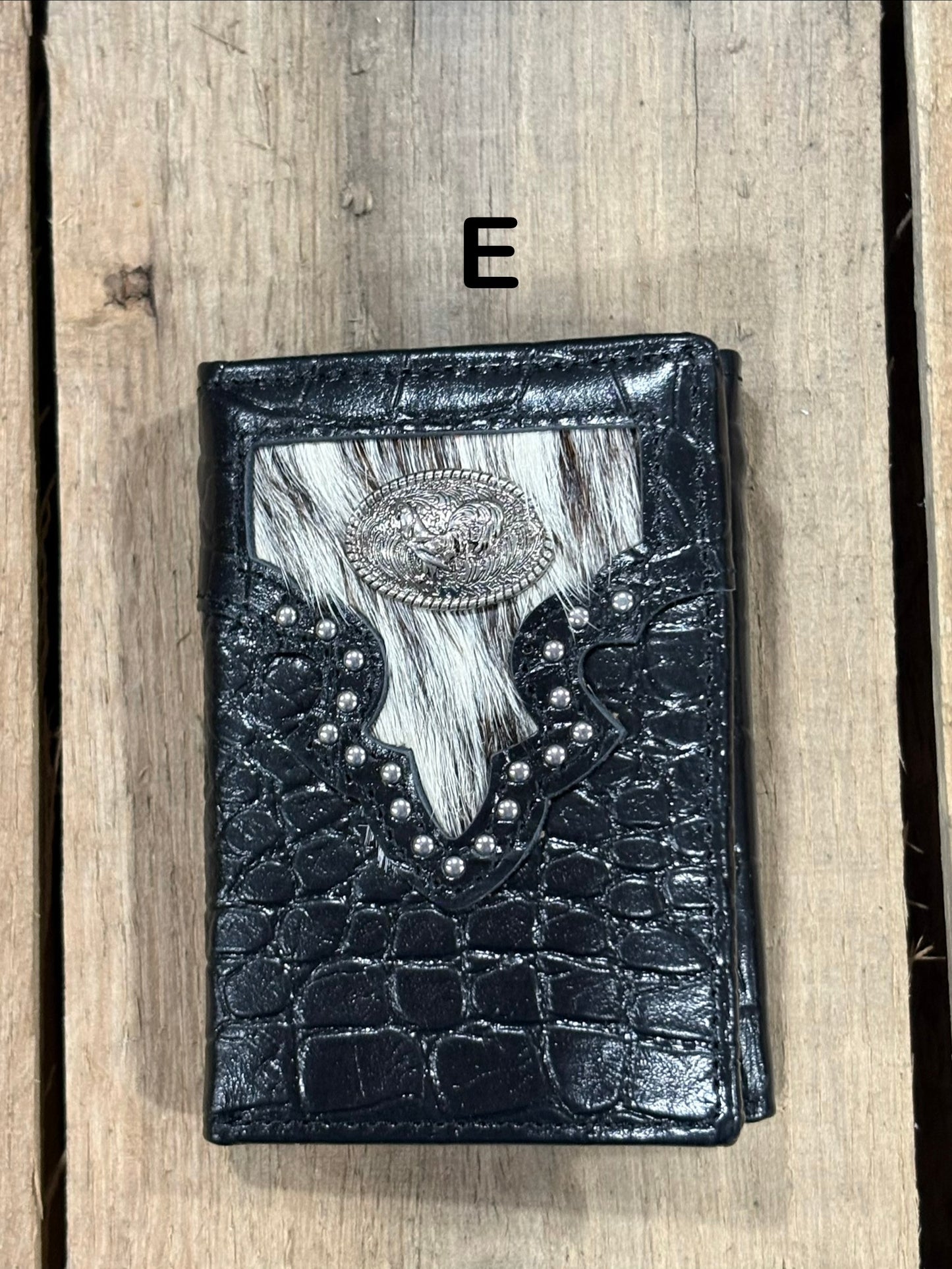 Black leather alligator print wallet with hairon cowhide and silver rooster concho on a wooden surface