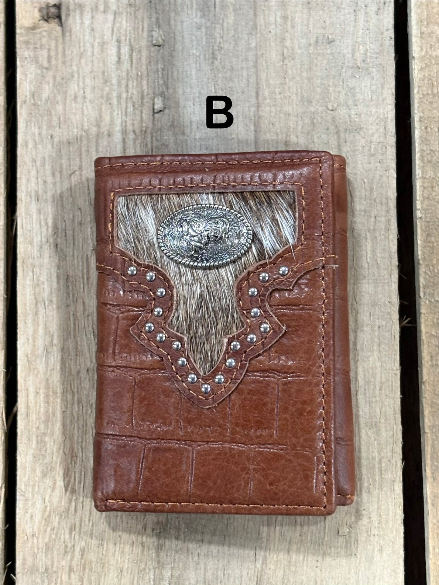 Brown leather alligator print wallet with hairon cowhide and silver rooster concho on a wooden surface