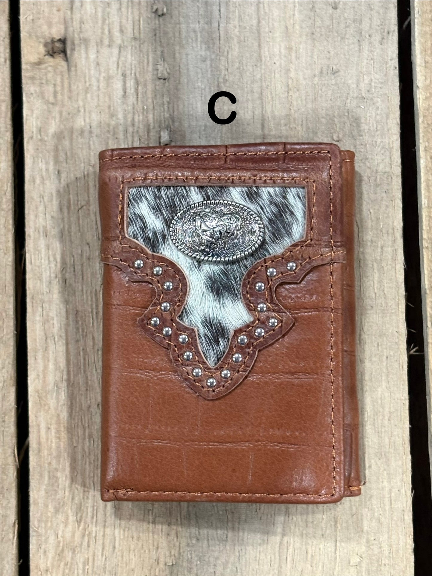 Brown leather alligator print wallet with hairon cowhide and silver rooster concho on a wooden surface