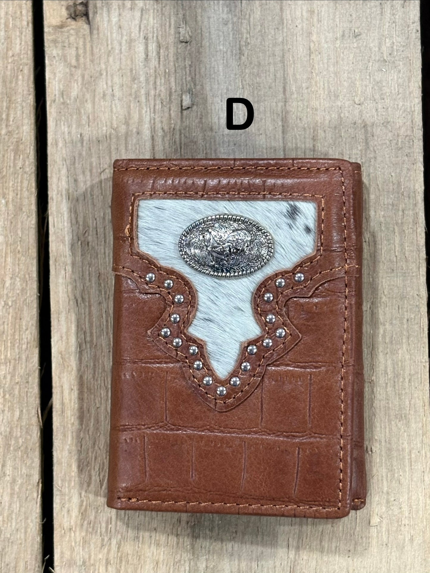 Brown leather alligator print wallet with hairon cowhide and silver rooster concho on a wooden surface