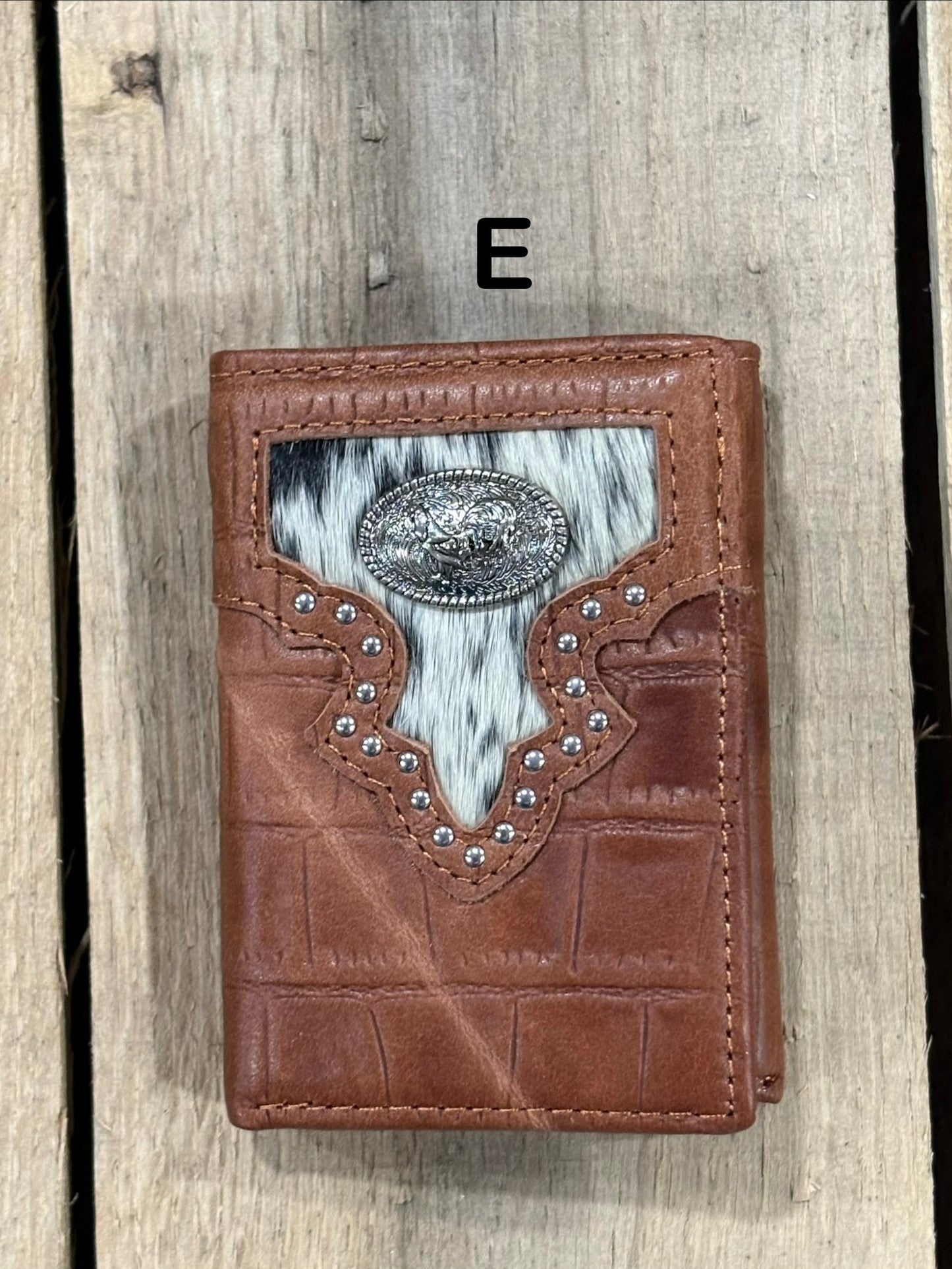 Brown leather alligator print wallet with hairon cowhide and silver rooster concho on a wooden surface