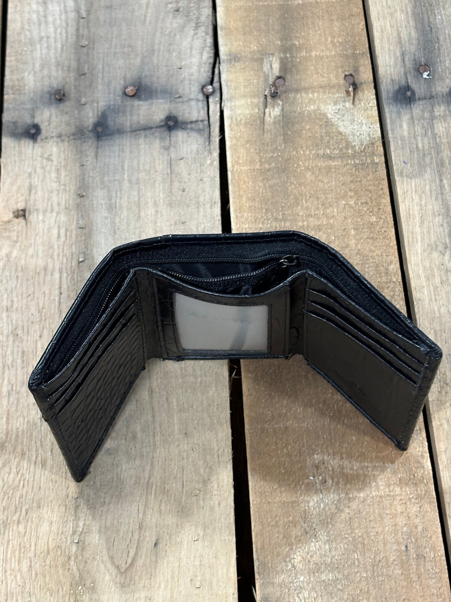 Black alligator print leather trifold wallet with a inside view of a ID window slot in the center, six card slots on the sides, and currency slot and zipper pocket compartment. 