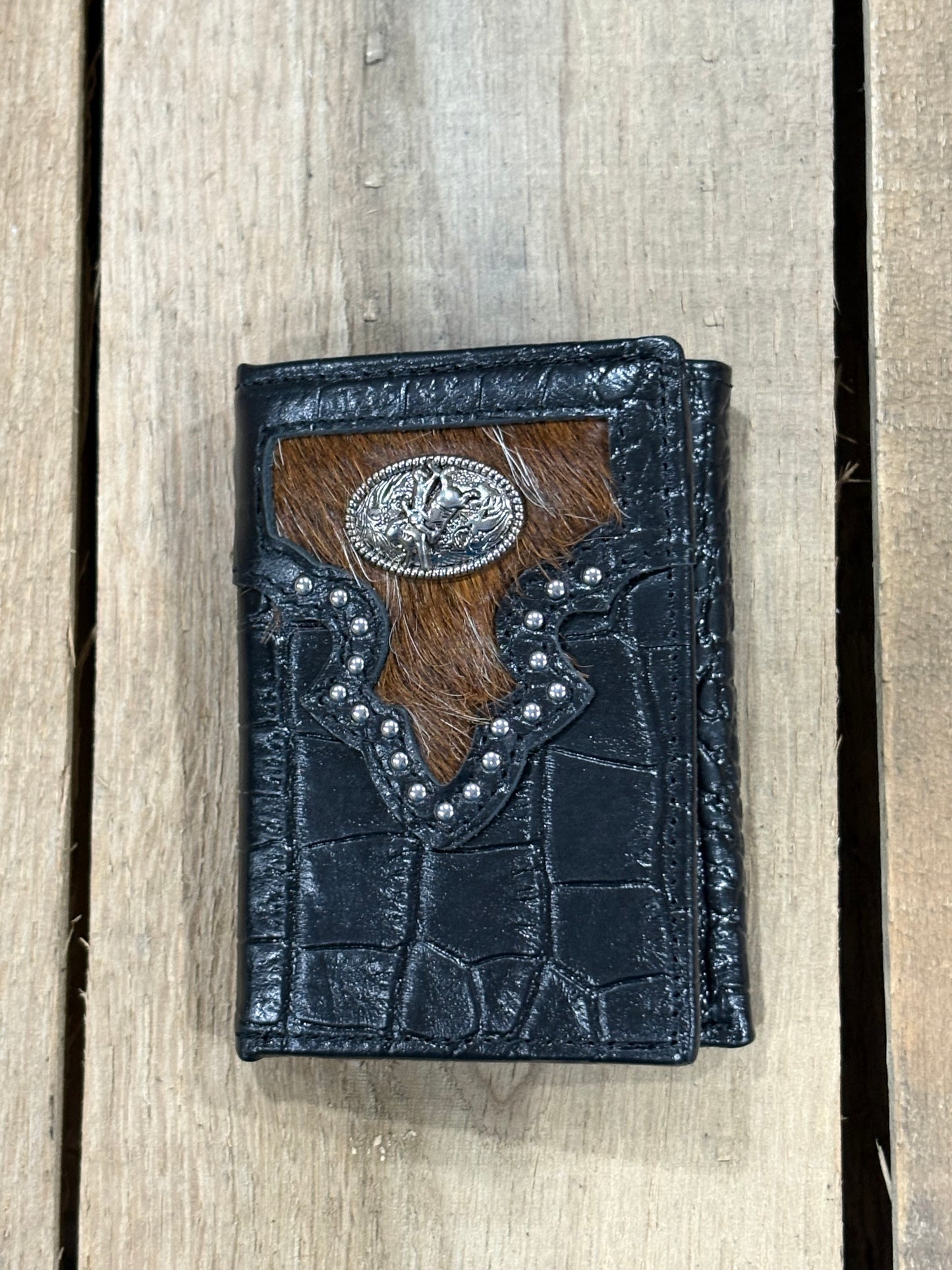 Black leather alligator print wallet with hairon cowhide and silver Bull Rider concho on a wooden surface