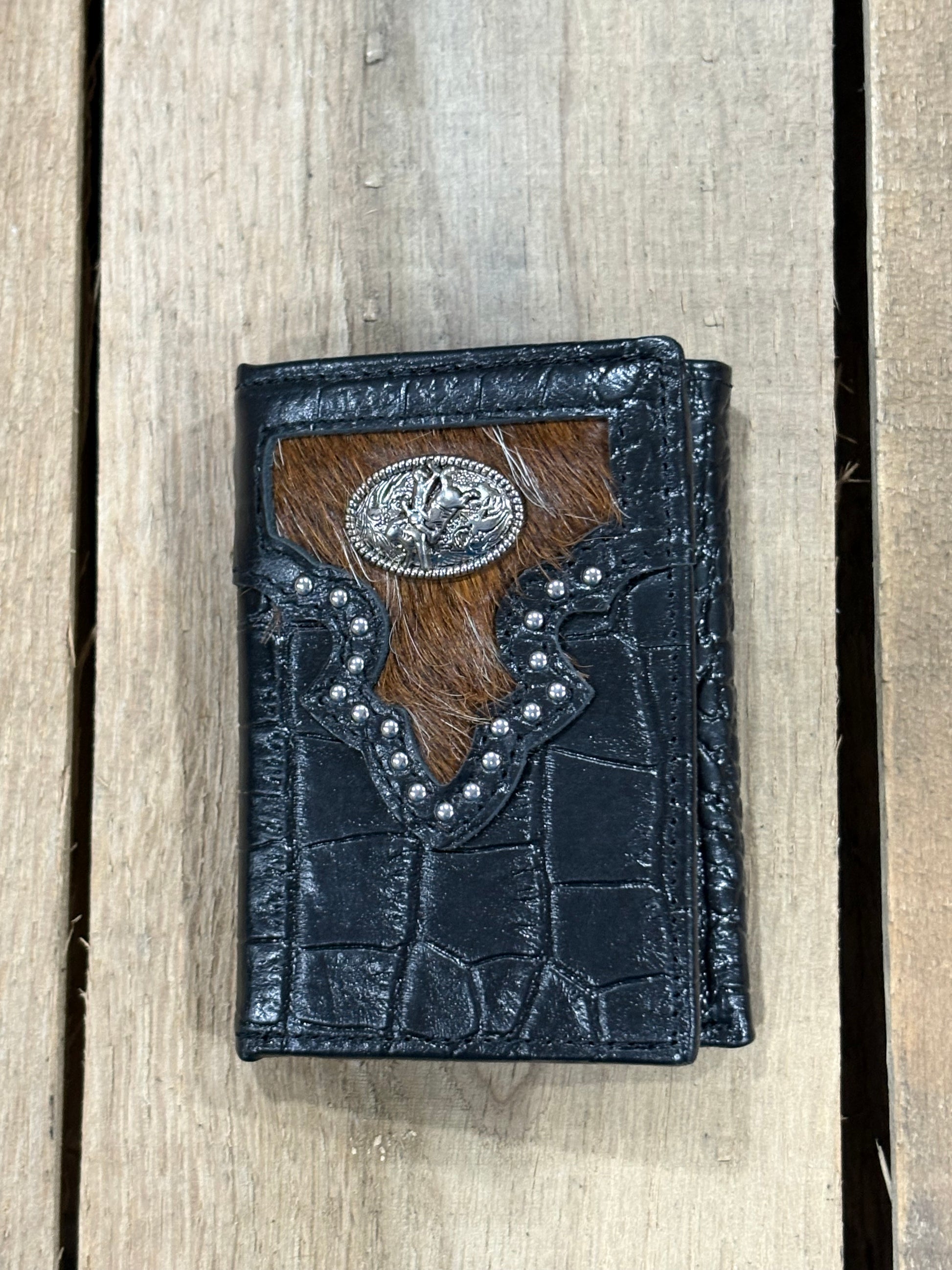 Black leather alligator print wallet with hairon cowhide and silver Bull Rider concho on a wooden surface