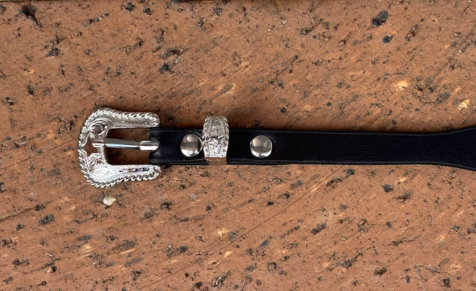 Black leather hat band with a Bull Rider Concho separated by Silver bands.  Close up view of buckle. 