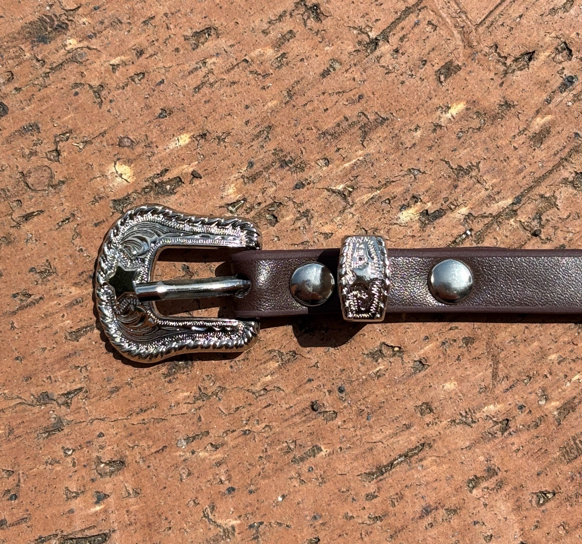 Coffee Brown leather hat band with Horse Head Concho and silver bands separating Conchos. Close up view of western style buckle. 