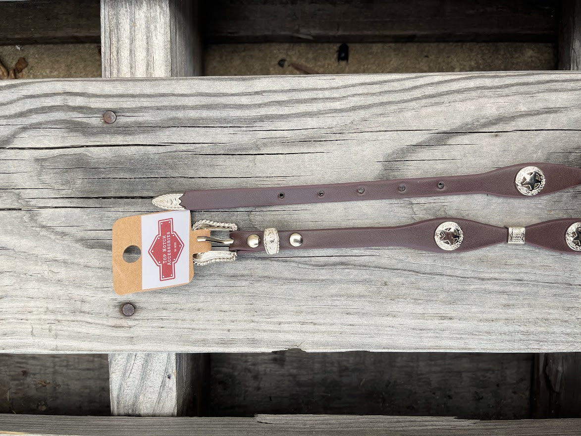 Decorative Coffee Brown leather hat band and silver buckle set and conchos on a wooden background