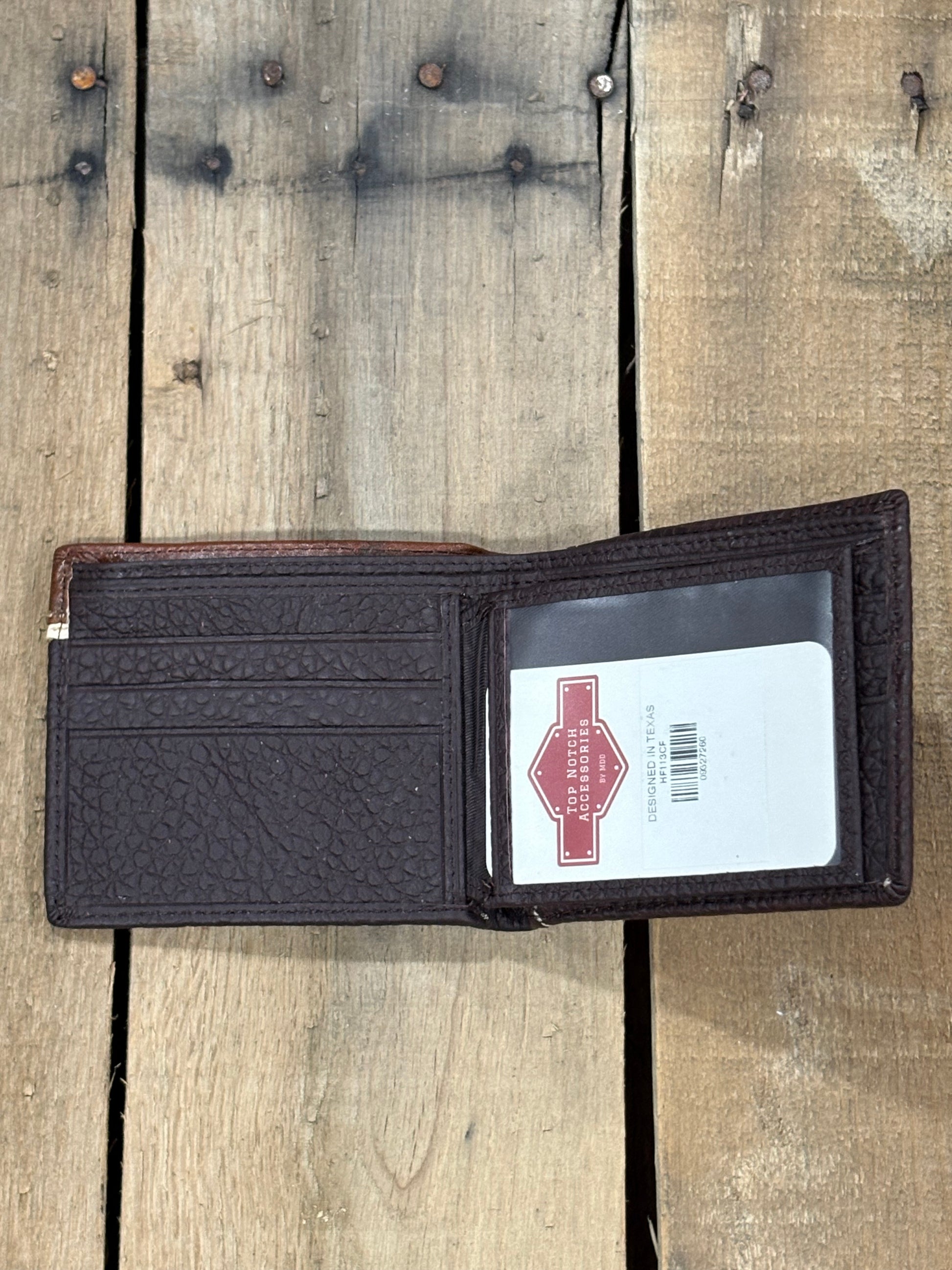 Coffee Brown pebbled leather wallet with three card slots and a Top Notch Accessories card inside the ID window slot a brand label on a wooden surface