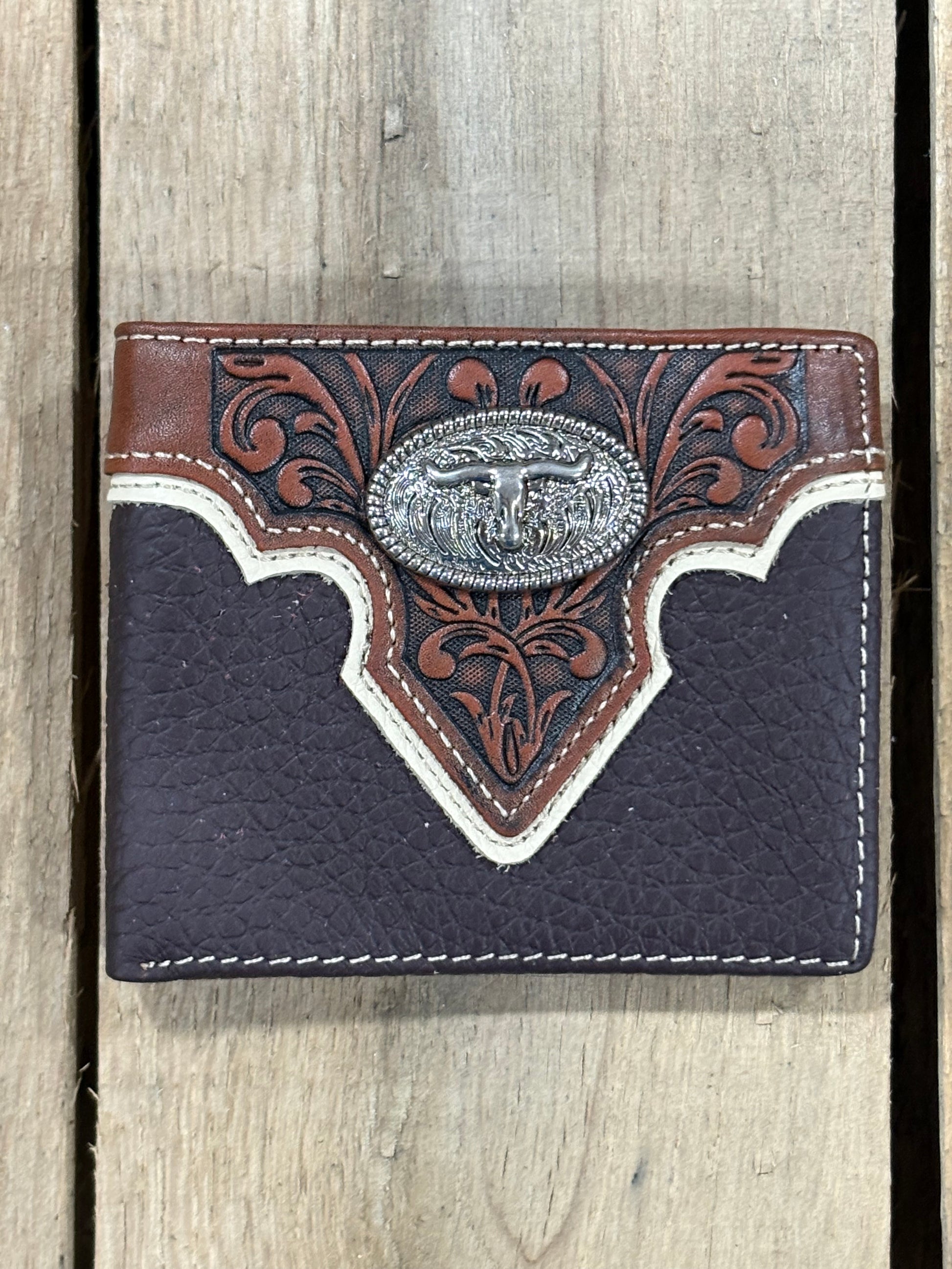 Coffee Brown pebbled leather wallet with intricate floral design that has a longhorn Concho on a wooden surface