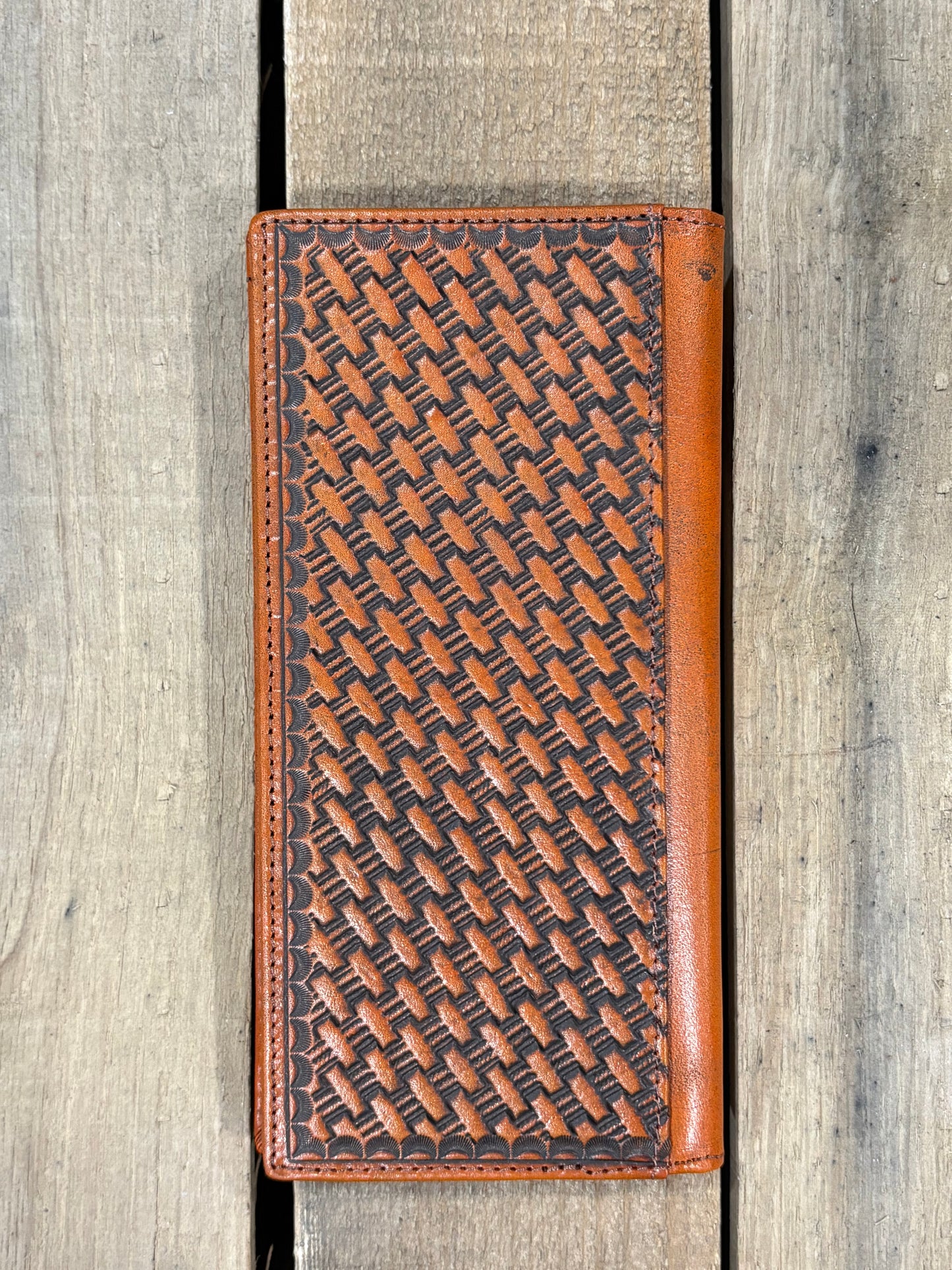 Brown leather wallet with embossed basketweave design on a wooden surface