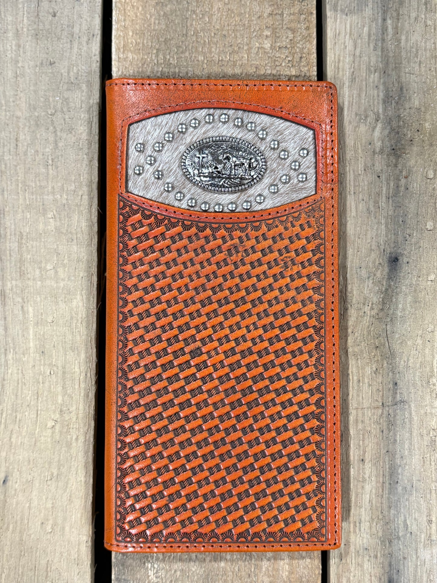 Brown leather wallet with praying cowboy silver concho with embossed basketweave design on a wooden surface