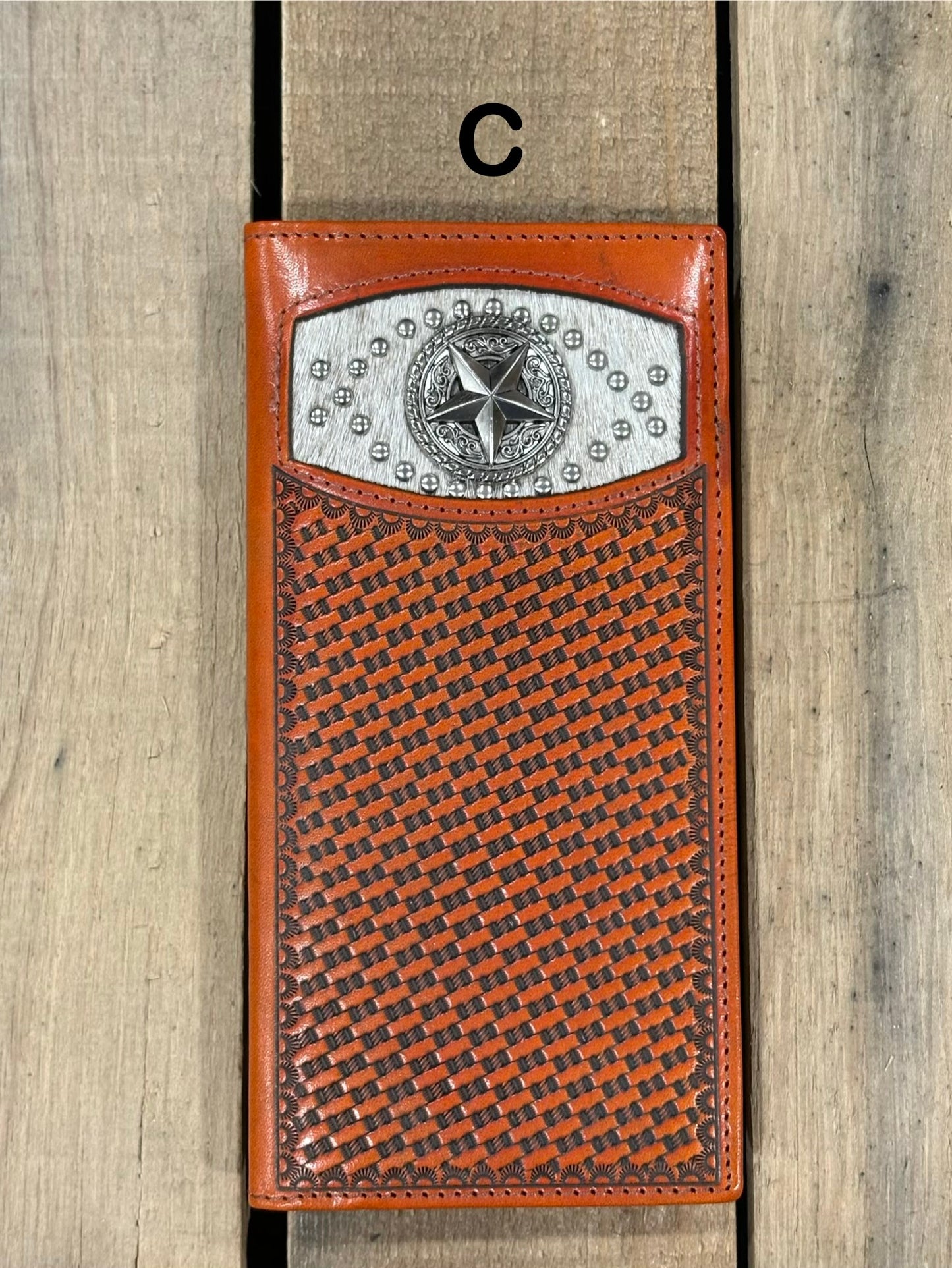 Brown leather wallet with star silver concho with embossed basketweave design on a wooden surface
