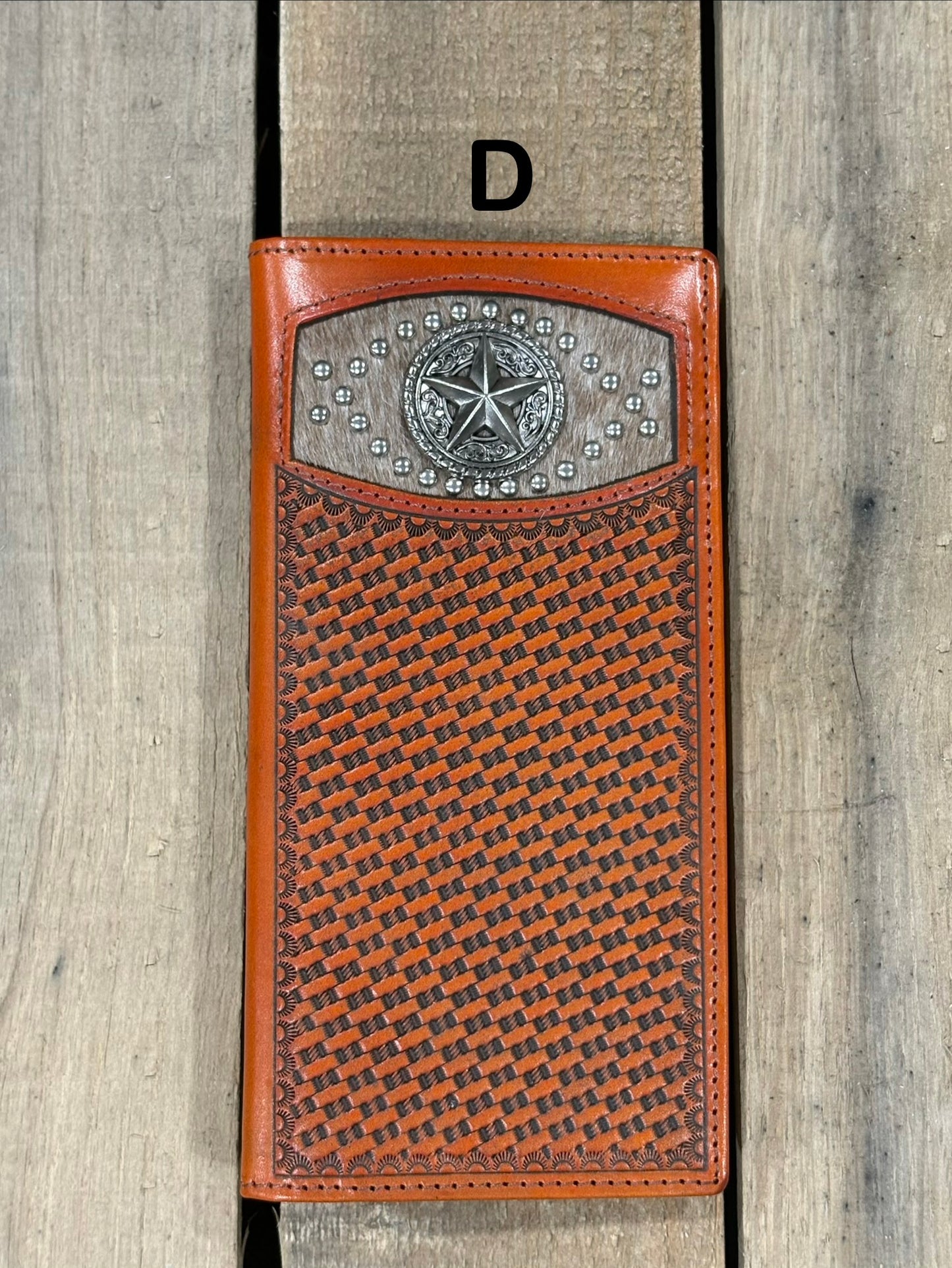 Brown leather wallet with star silver concho with embossed basketweave design on a wooden surface