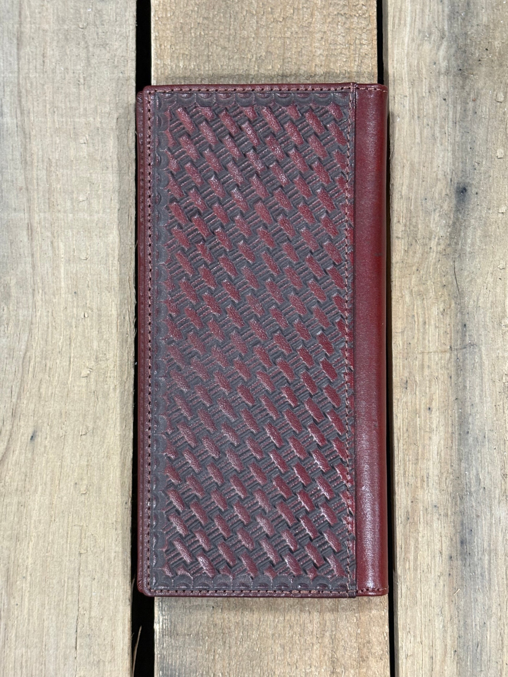 Brown leather wallet with embossed pattern on a wooden surface