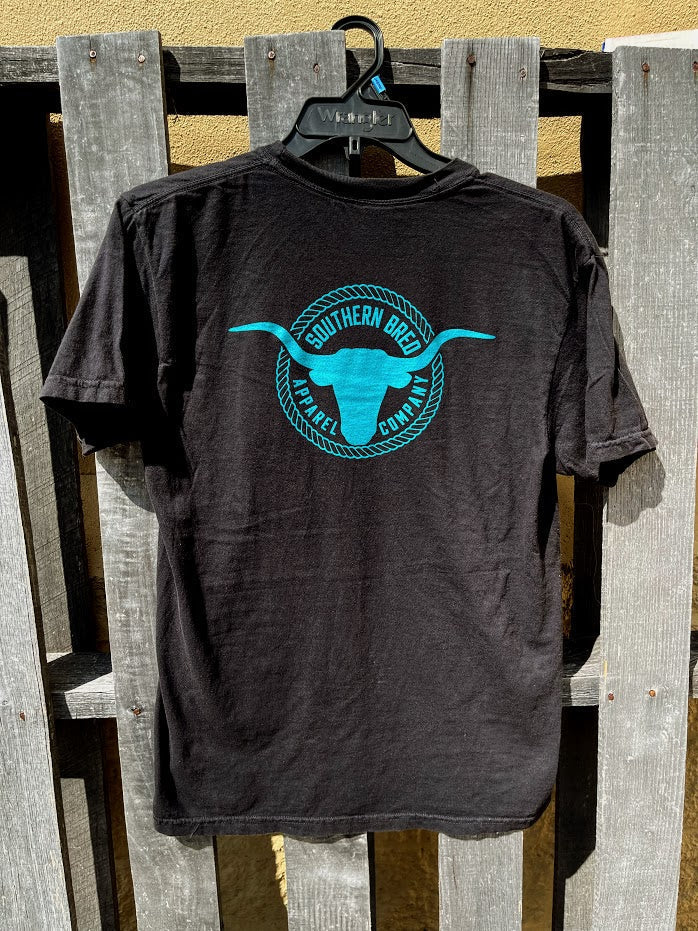 Black t-shirt with a blue logo hanging on a wooden fence