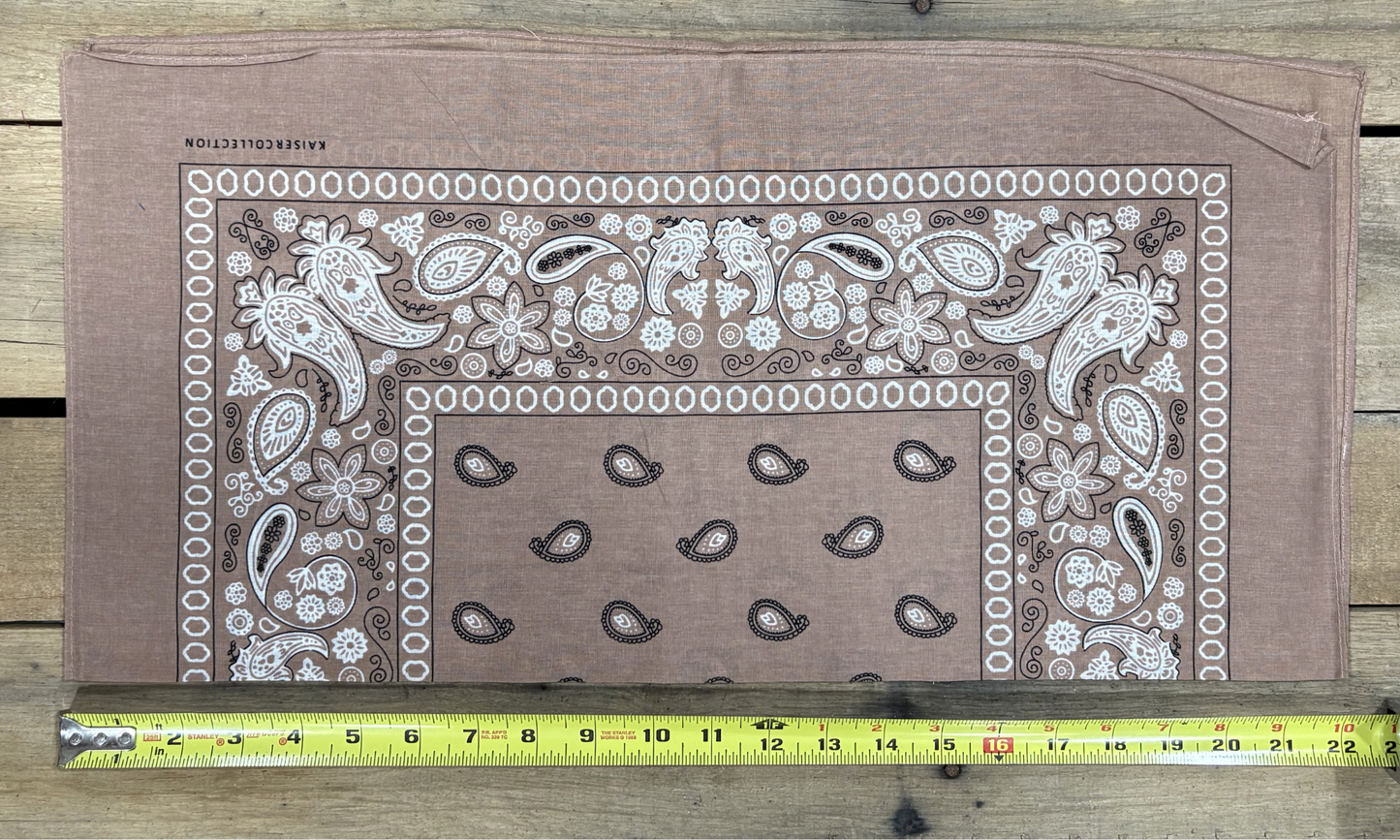 Natural Brown bandana with white paisley patterns on a wooden surface, measured by a yellow tape measure.