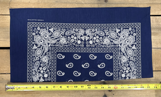 Navy bandana with white paisley patterns on a wooden surface, measured by a yellow tape measure.