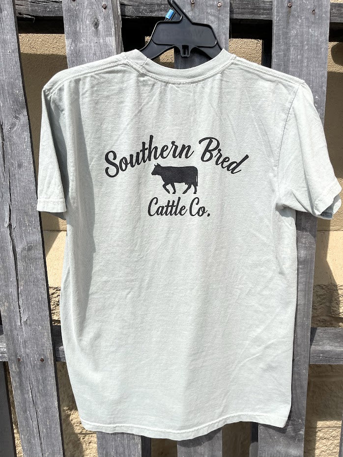 Bay t-shirt with 'Southern Bred Cattle Co.' Black text and cow silhouette on a wooden background