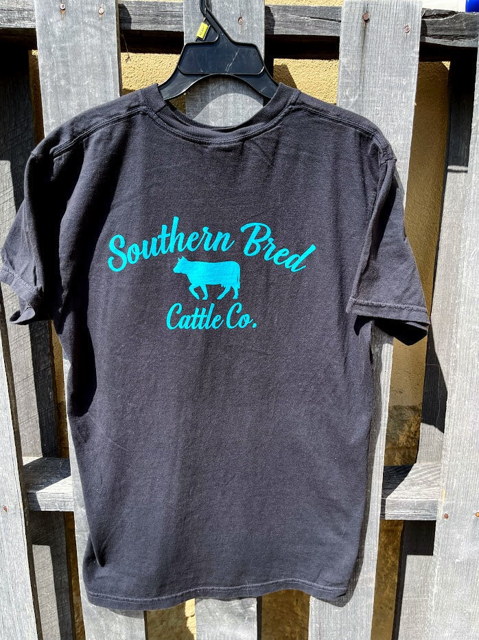 Black t-shirt with 'Southern Bred Cattle Co.' Teal text and logo on a wooden background