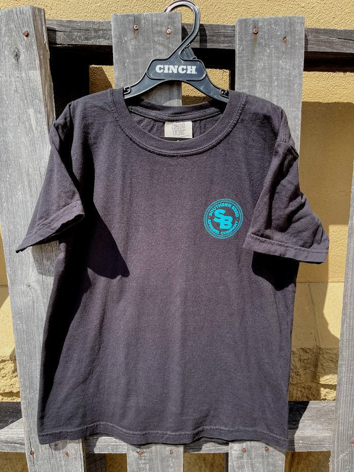 Black t-shirt with a Teal logo on a hanger against a wooden background