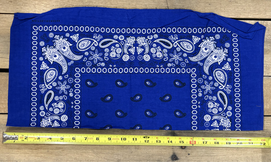Royal Blue bandana with white paisley patterns on a wooden surface, measured by a yellow tape measure.