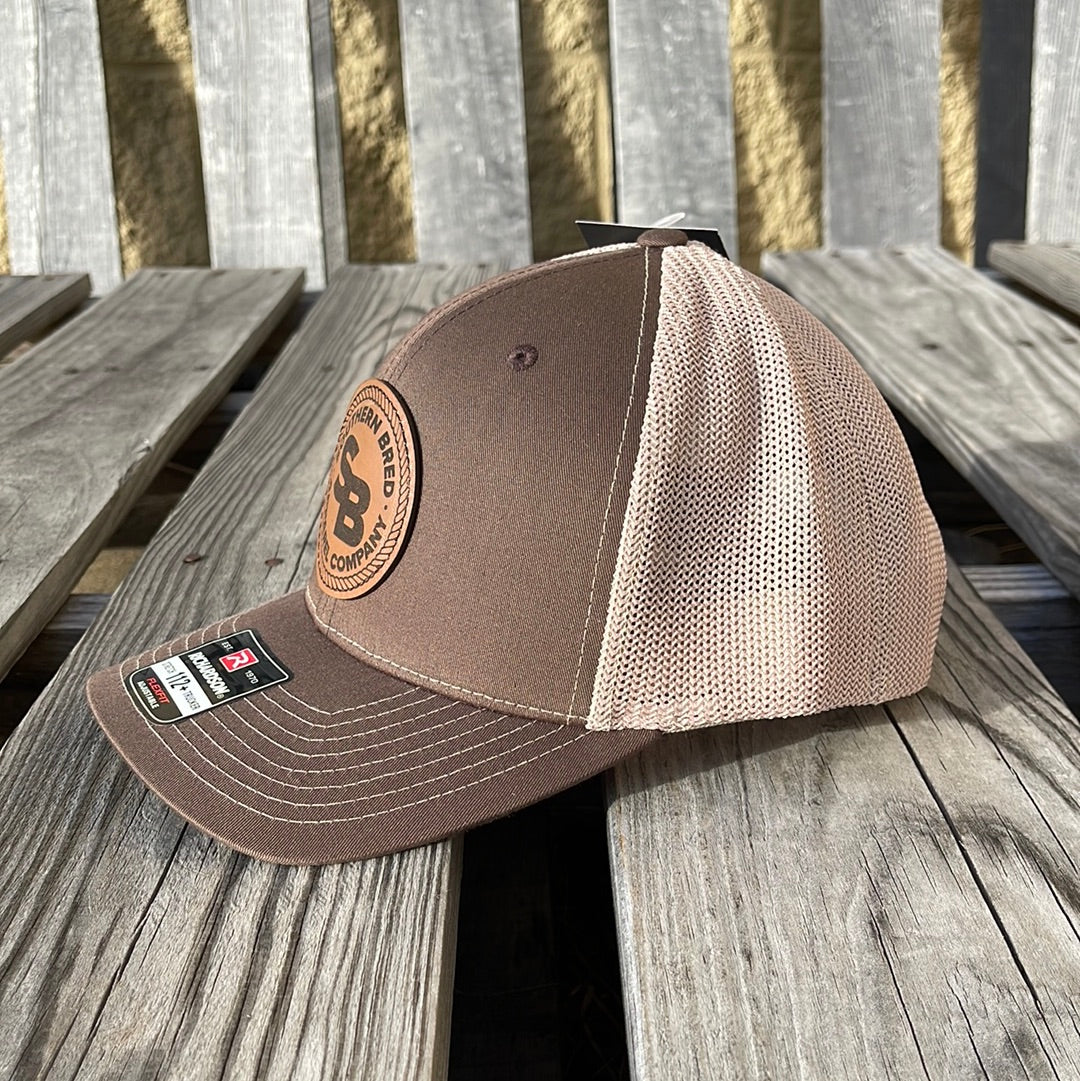 Brown and beige baseball cap with leather patch on wooden surface