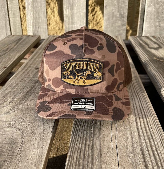 Camouflage baseball cap with a patch on a wooden surface